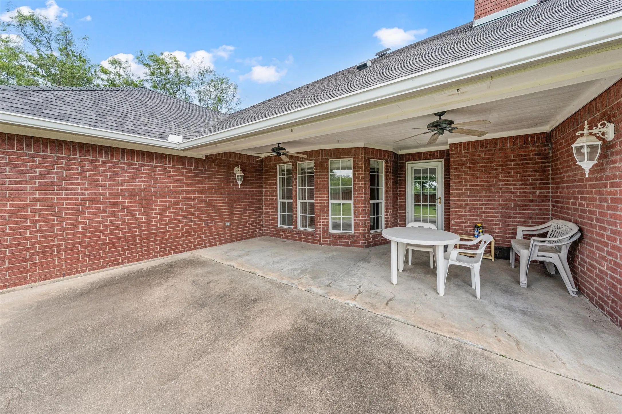 Covered patio featuring red brick exterior walls and a concrete surface