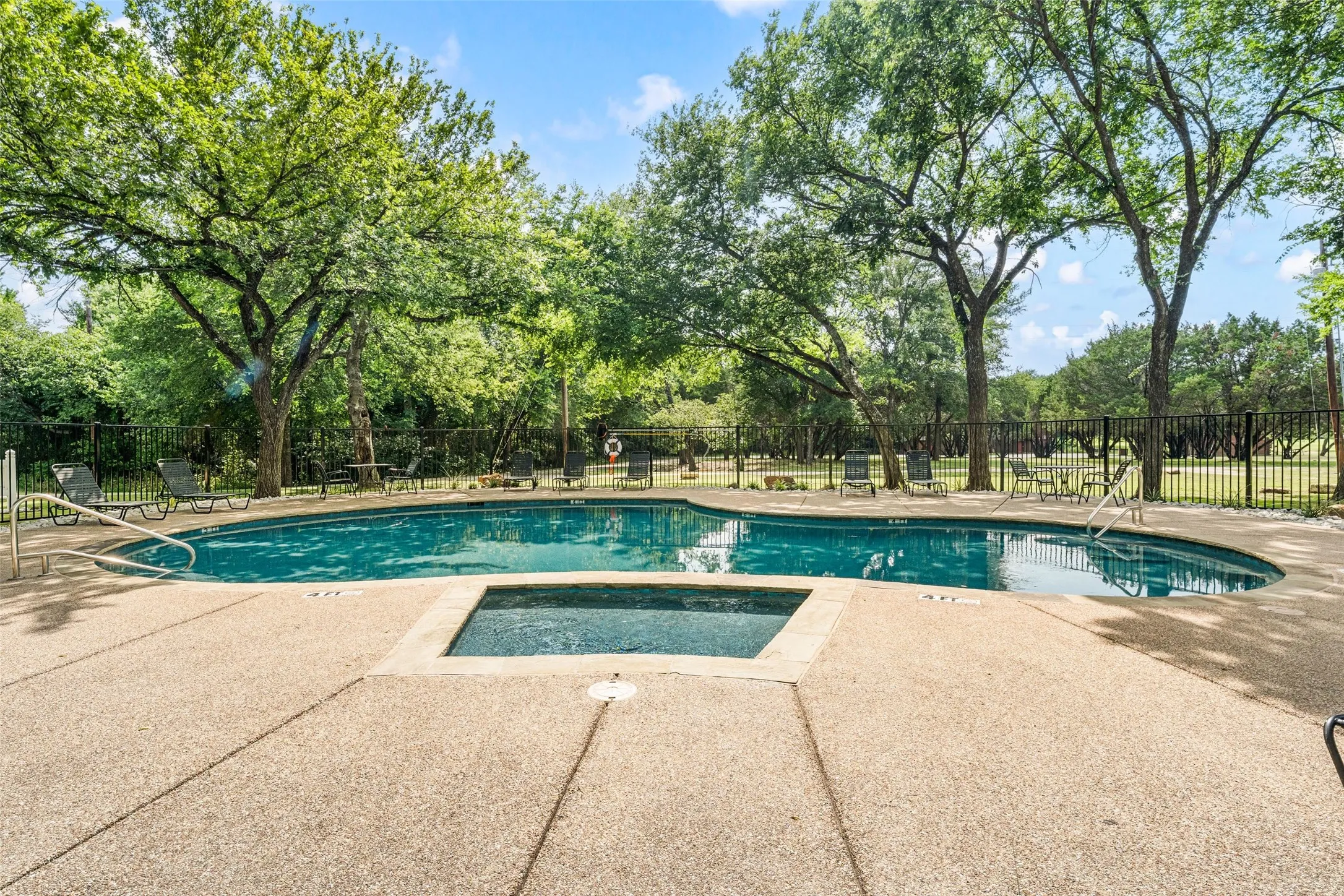 Swimming pool with an integrated spa, surrounded by an exposed aggregate concrete deck