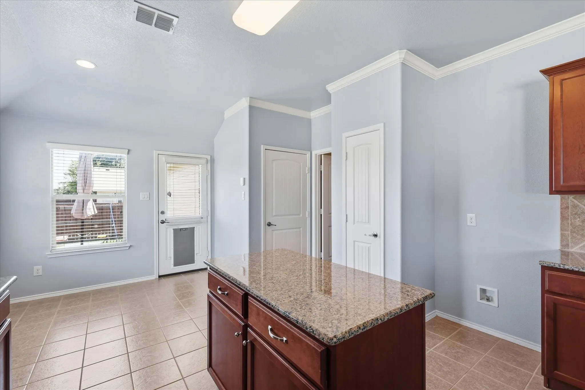 Kitchen island with granite countertop and rich wood cabinetry