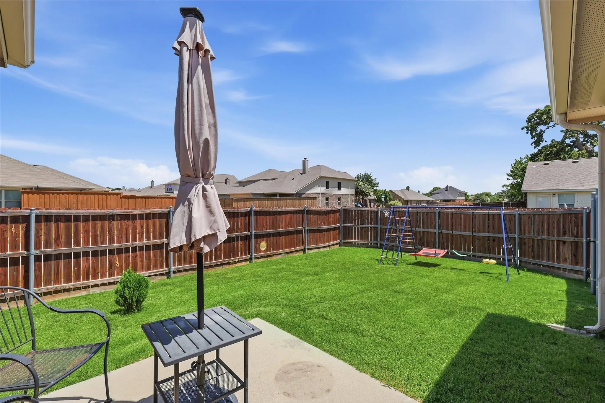 Private backyard featuring a concrete patio, wood privacy fencing, and a manicured lawn