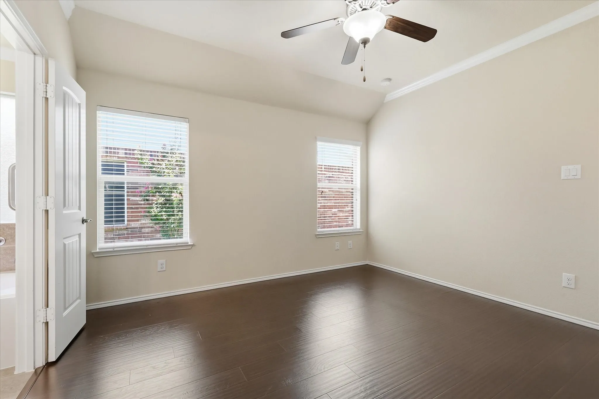 Room featuring dark wood-finish flooring, vaulted ceiling, and crown molding