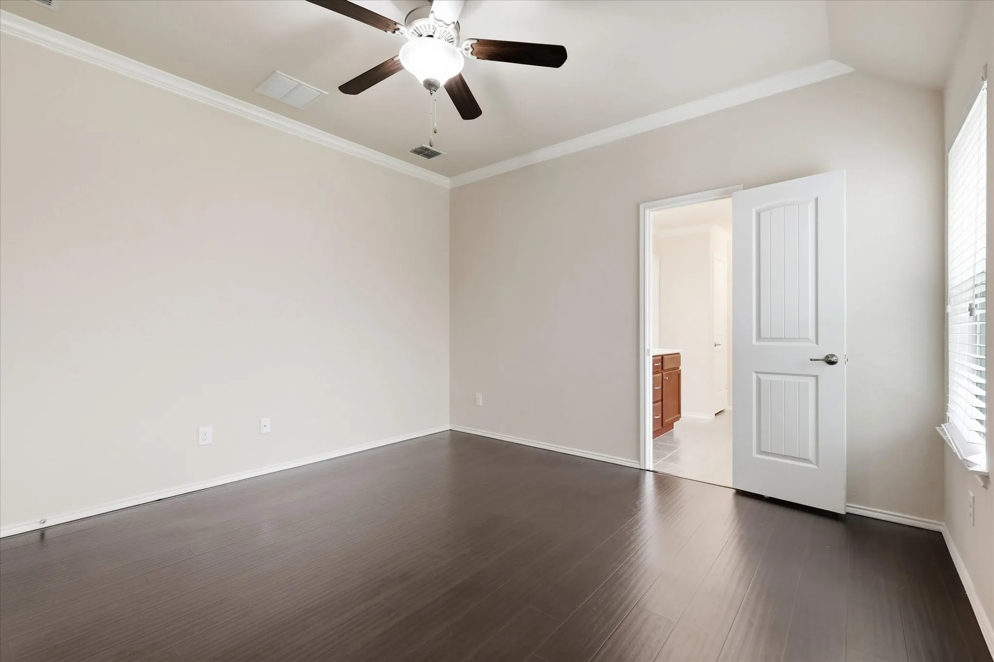 Primary bedroom with wood-finish flooring, vaulted ceiling, and a ceiling fan with integrated lighting