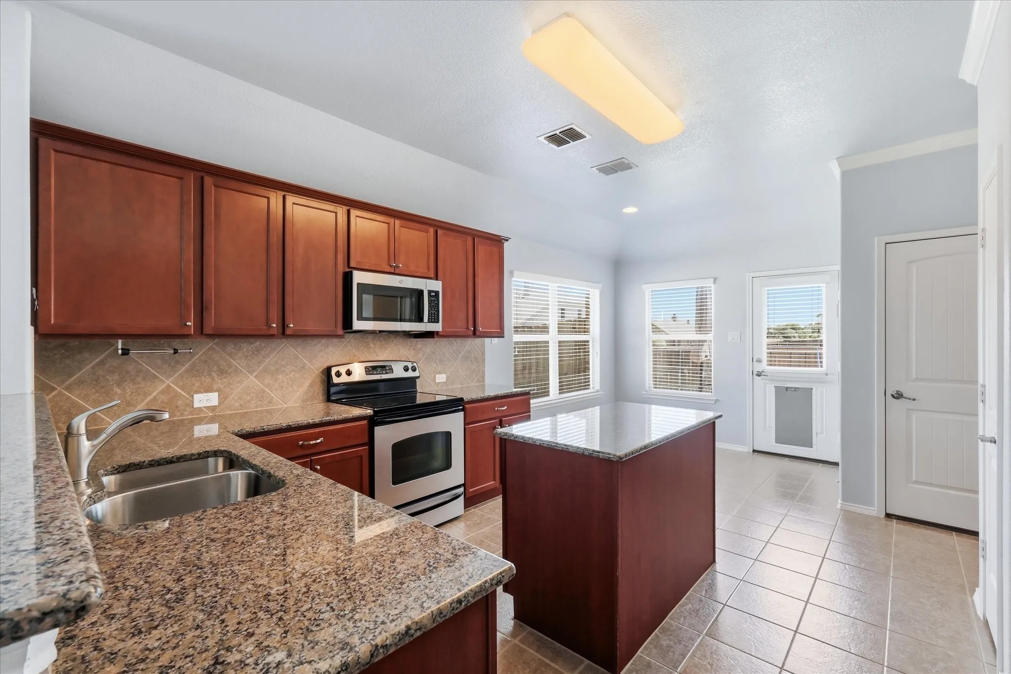 Kitchen featuring wood cabinetry, granite countertops, stainless steel appliances, and a central island