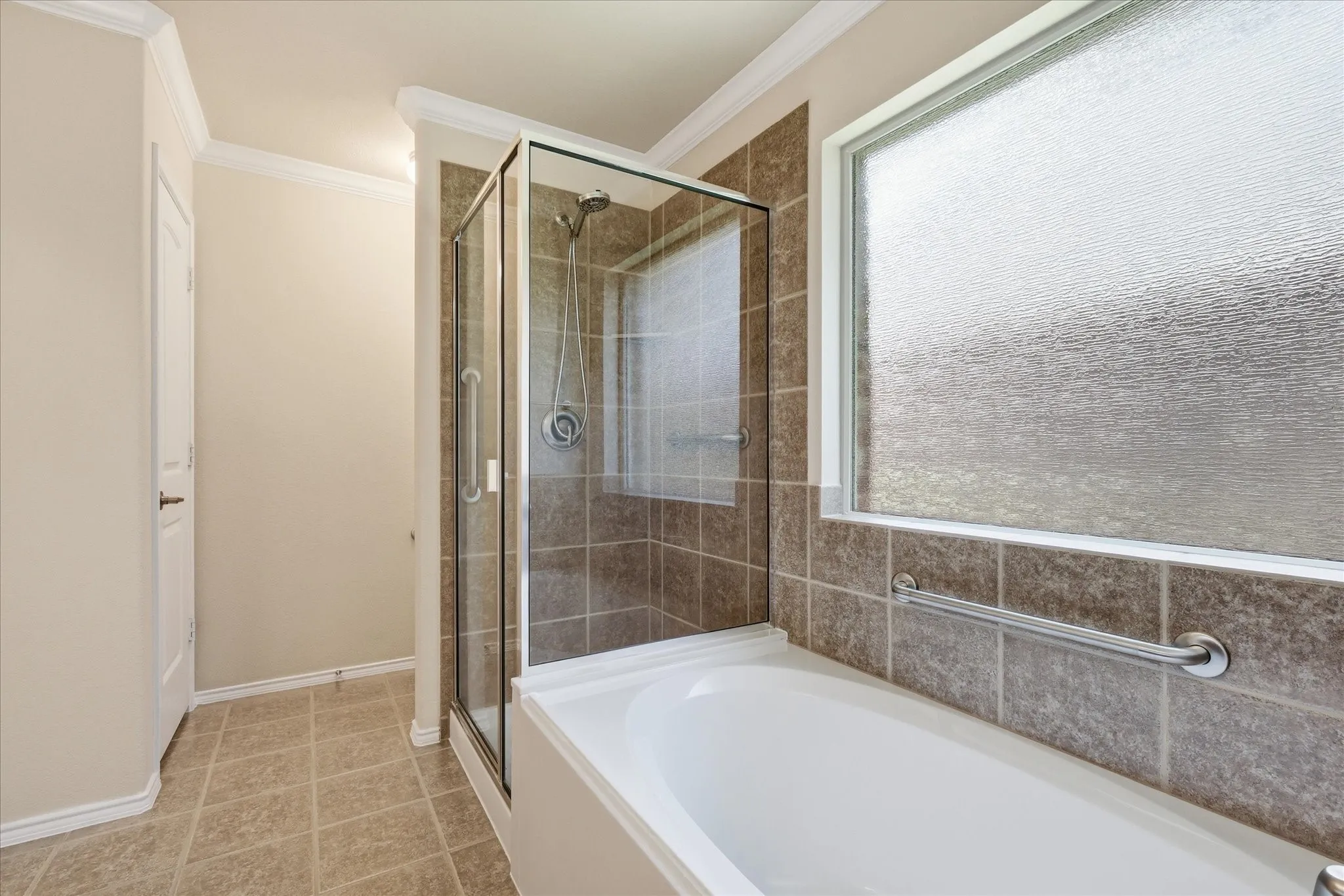 Bathroom featuring a glass-enclosed shower with tile surround, a soaking tub, and a large privacy window