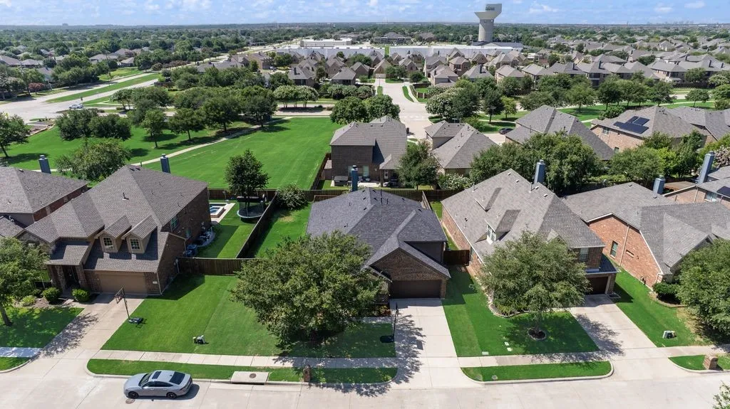 Residential neighborhood featuring uniform brick and stone facades, mature trees, and ample green space