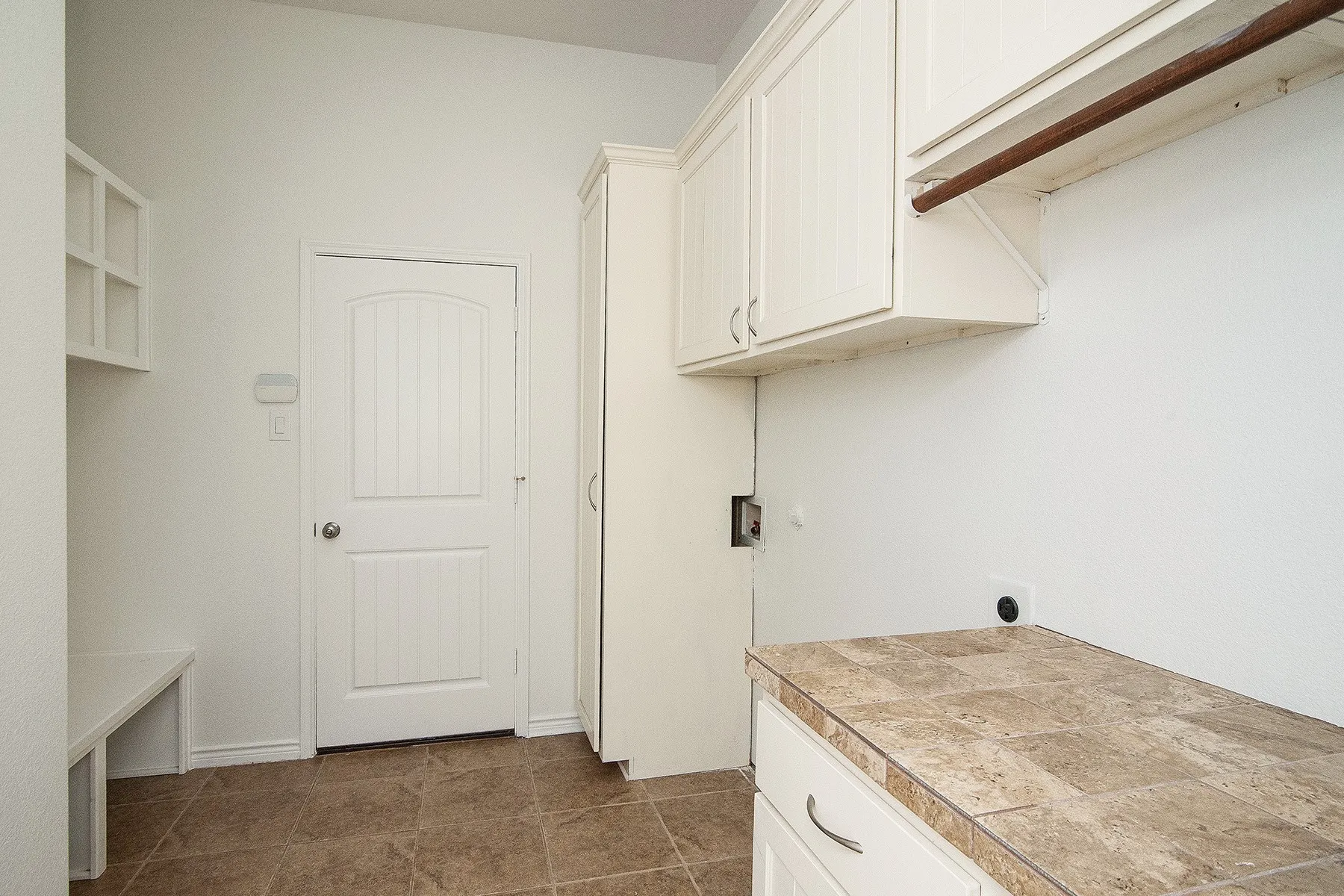 Laundry room featuring white cabinetry with ample storage, tile flooring, and a utility countertop with finished surface