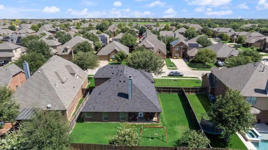 Expansive backyard featuring a manicured lawn, established trees, and a privacy fence