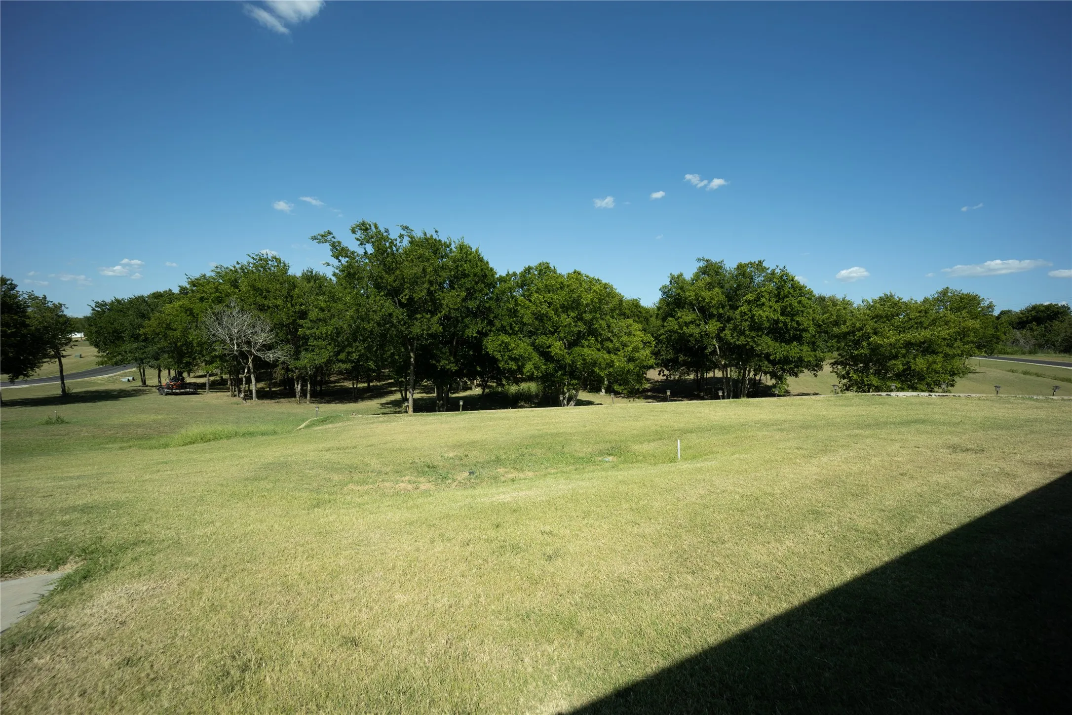 Expansive grassy area featuring a tree line at the perimeter