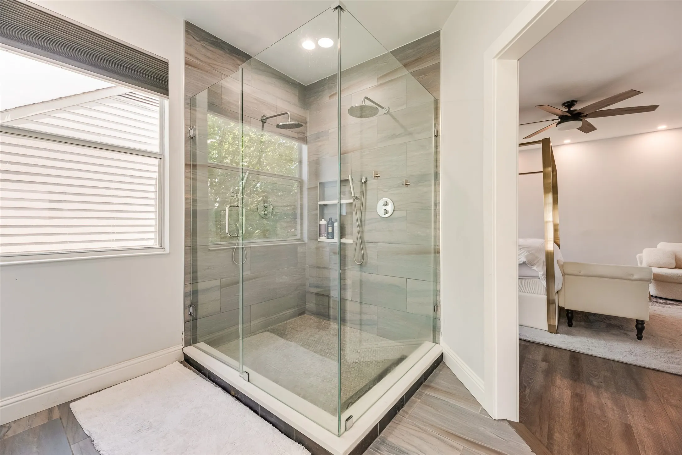 Glass-enclosed shower featuring large format tile, dual shower heads, and built-in shelving