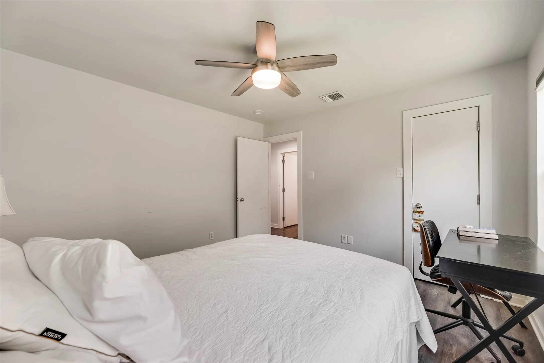 Bedroom featuring wood-finish flooring, a ceiling fan with integrated lighting, and light gray wall paint