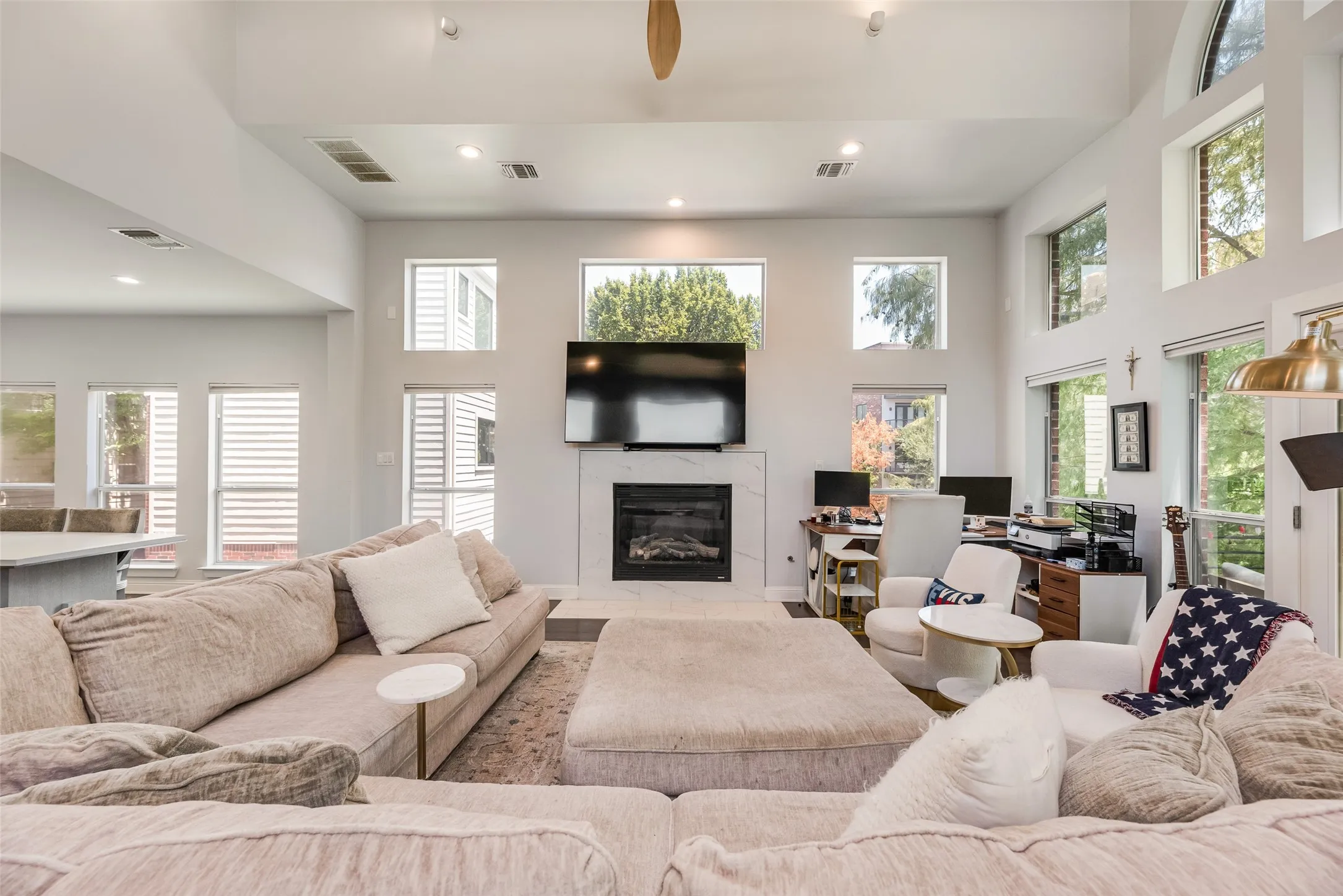 Spacious living area featuring a vaulted ceiling and an abundance of natural light from multiple windows