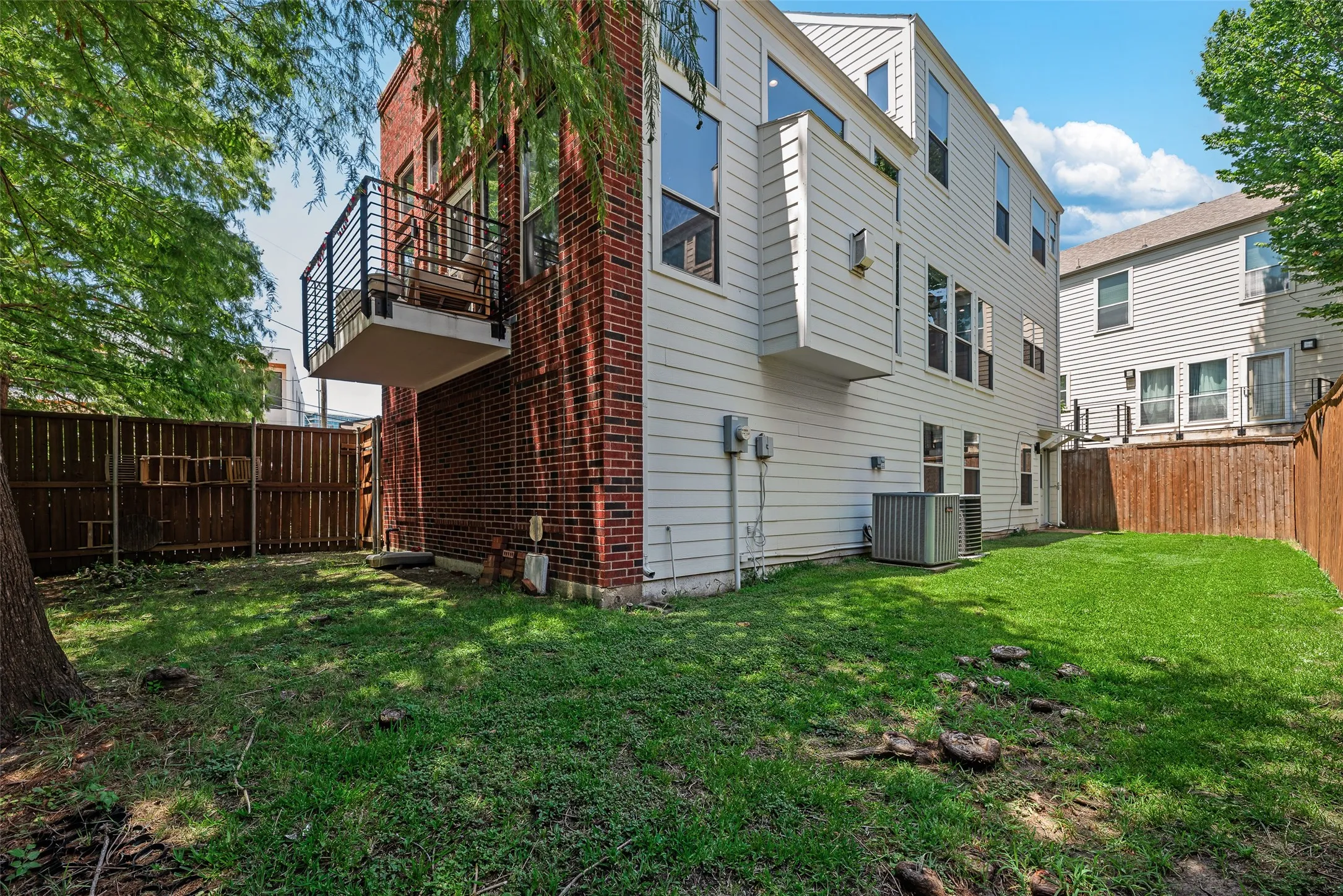 Private outdoor area featuring a manicured lawn, wood fencing, and mature trees