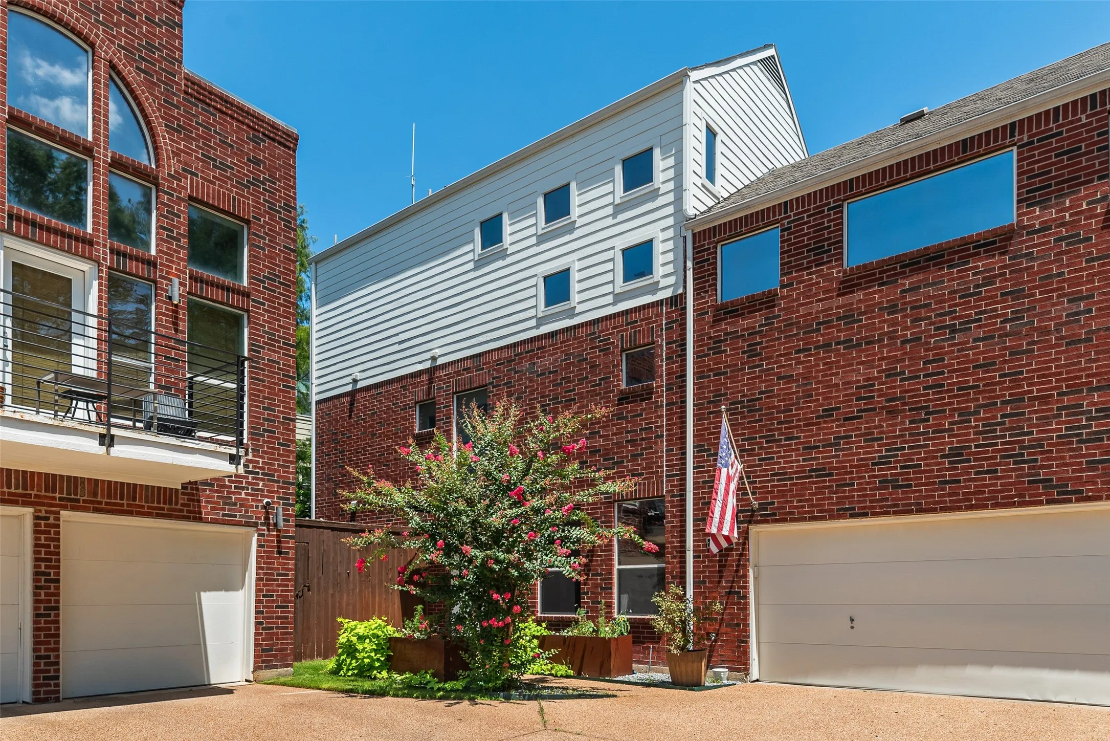 Brick facade residences featuring white garage doors and a shared paver driveway