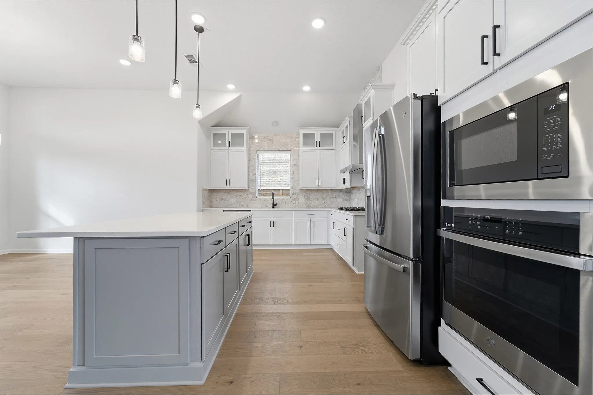 Spacious kitchen featuring a large central island with light gray cabinetry and a white countertop