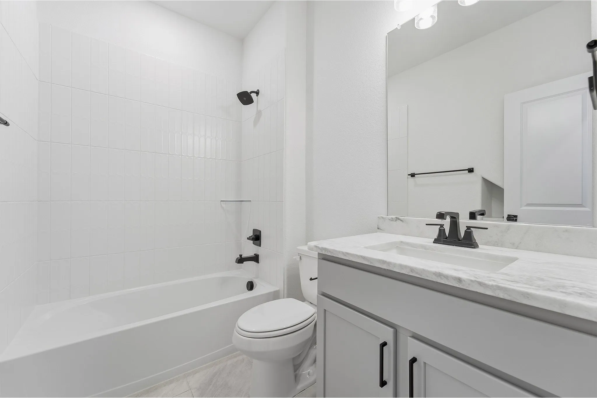 Contemporary bathroom featuring a white tub, subway tile shower surround, and matte black fixtures