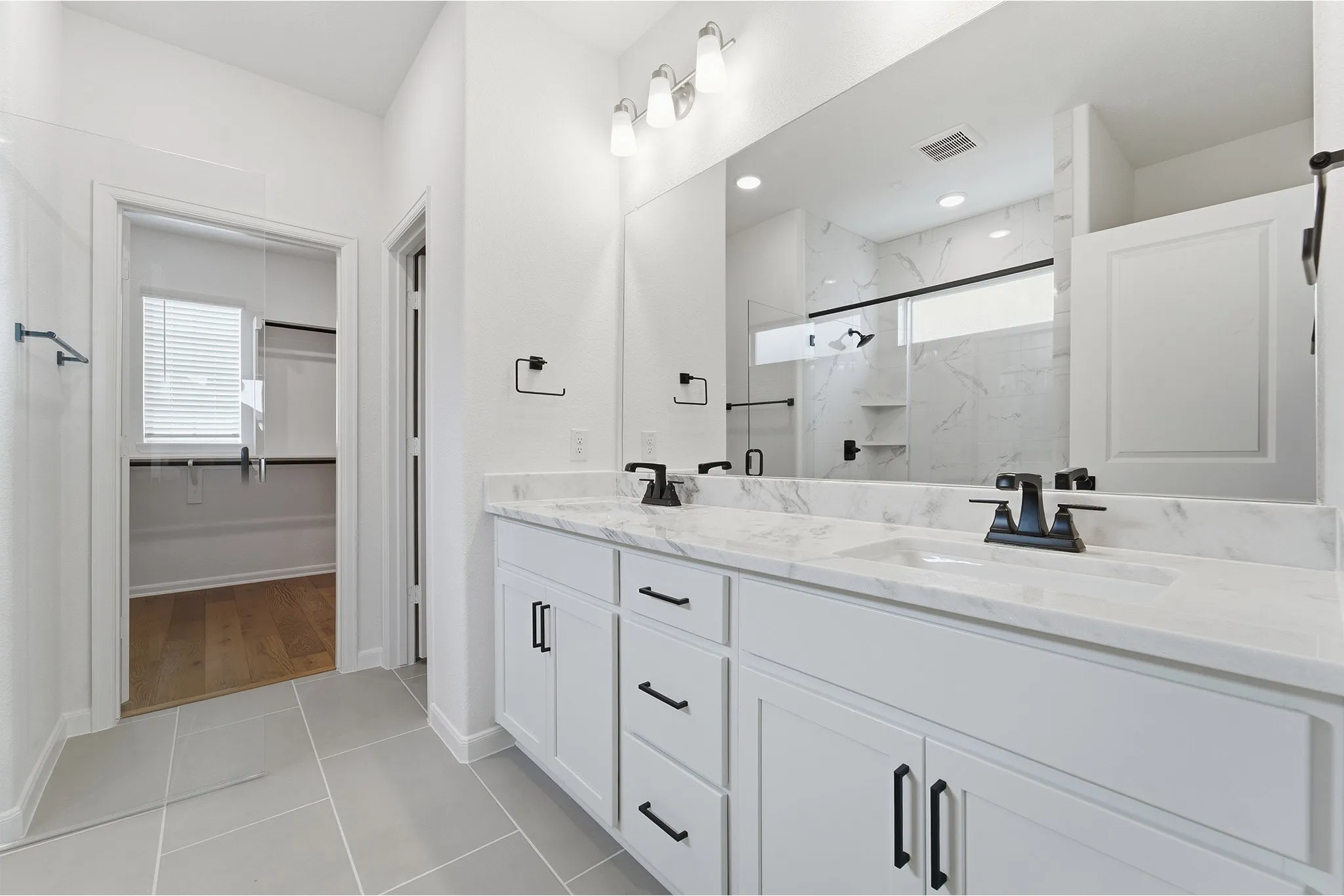 Bathroom featuring a dual vanity with white cabinetry, stone countertops, and matte black fixtures