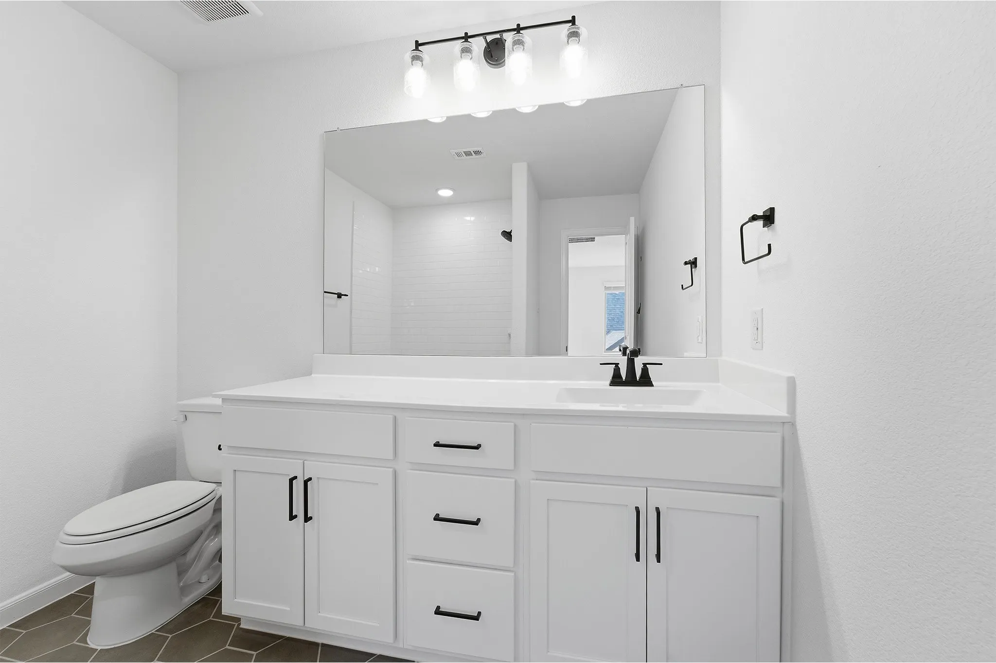 Bathroom featuring a white vanity with matte black hardware, a large mirror, and a three-light fixture