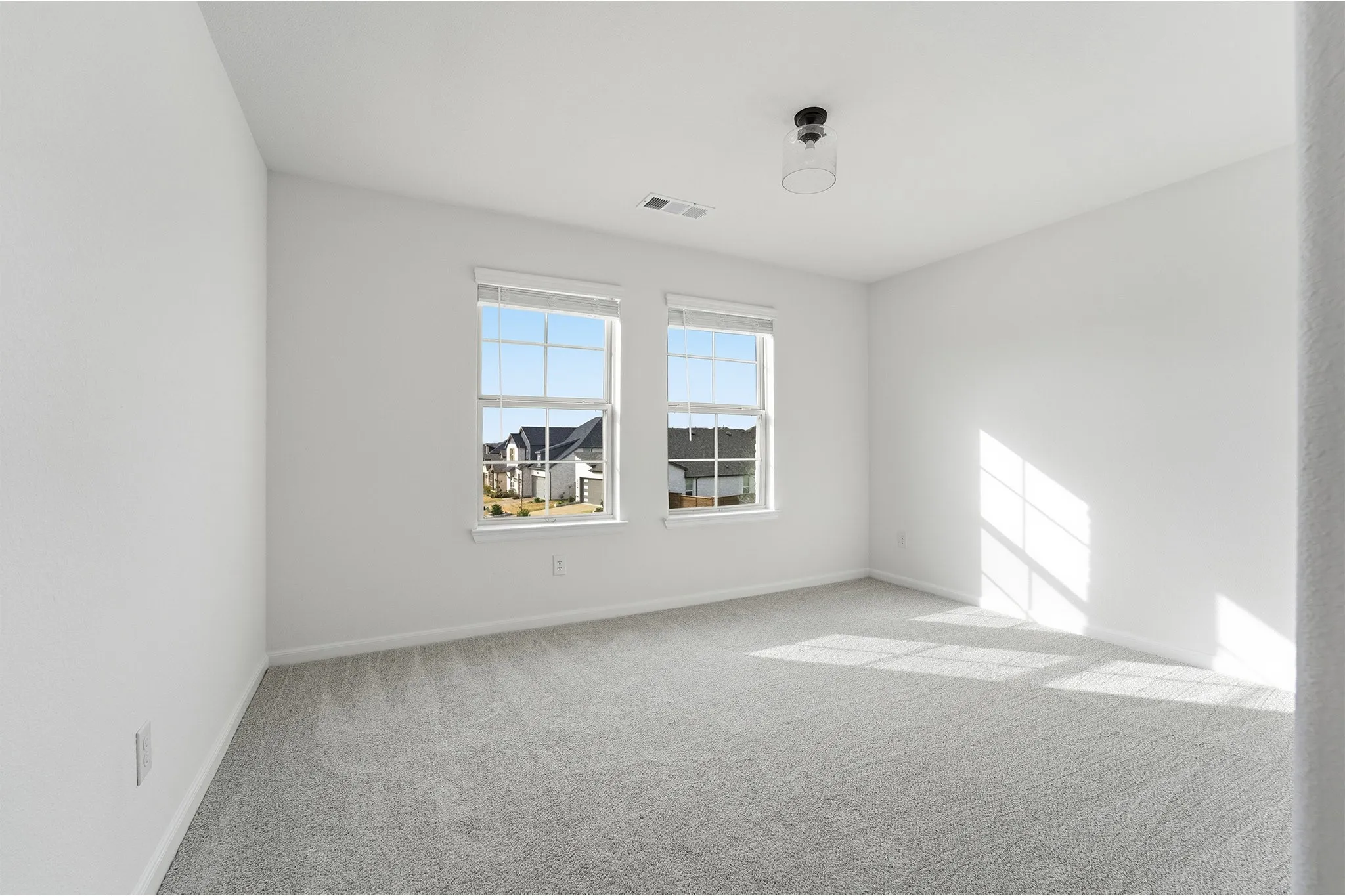 Bright interior space featuring two windows, light gray carpet, white painted walls, and a contemporary ceiling light fixture