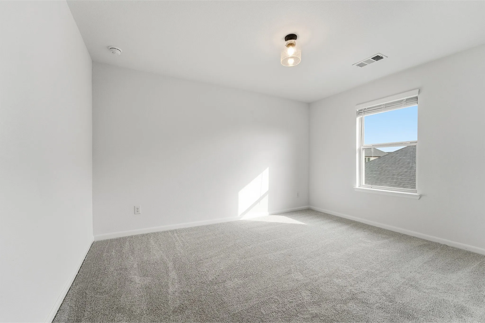 Spacious room featuring light gray carpeting, neutral wall paint, and a double-hung window