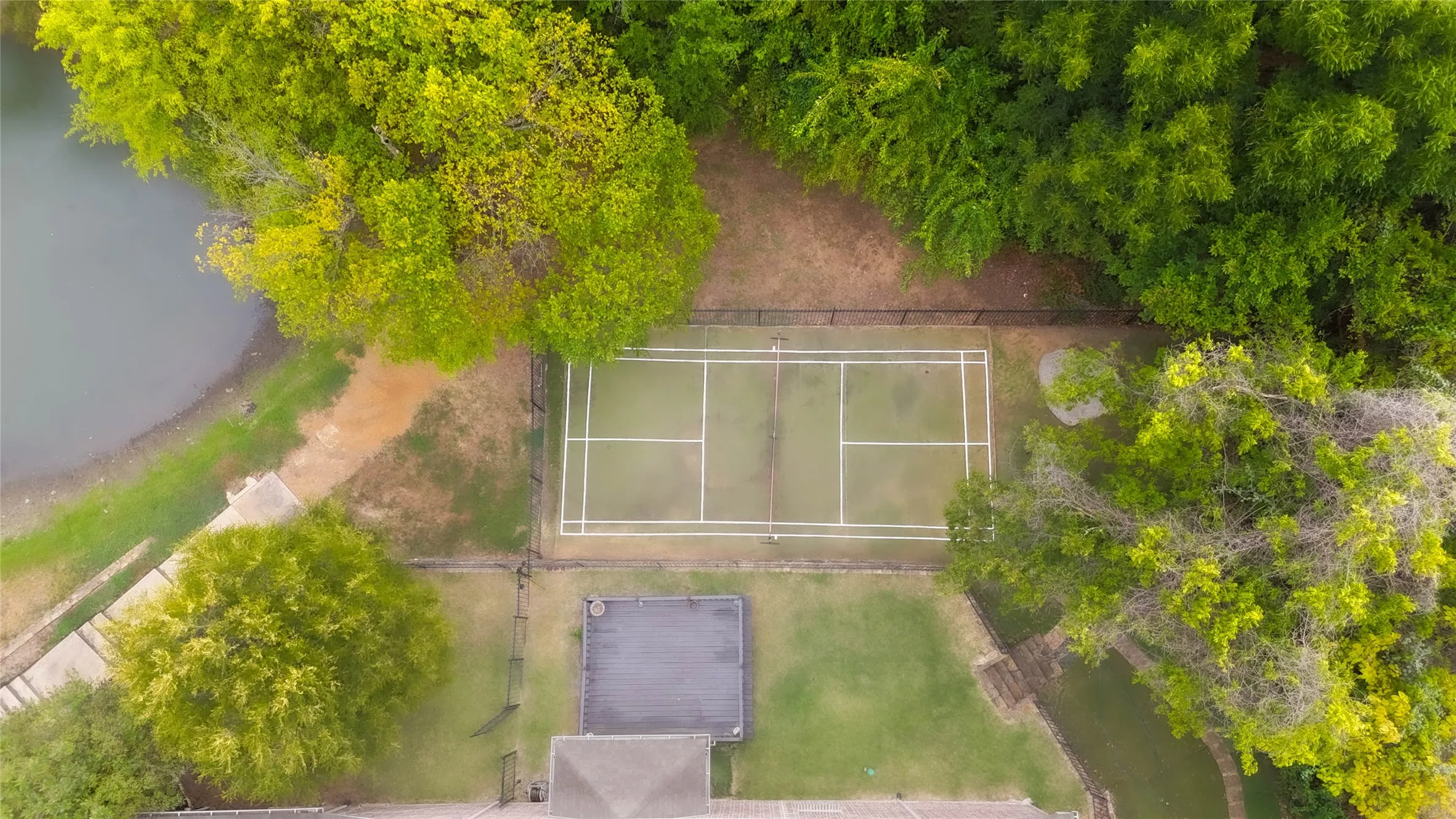 Fenced recreational court, mature trees, and a body of water