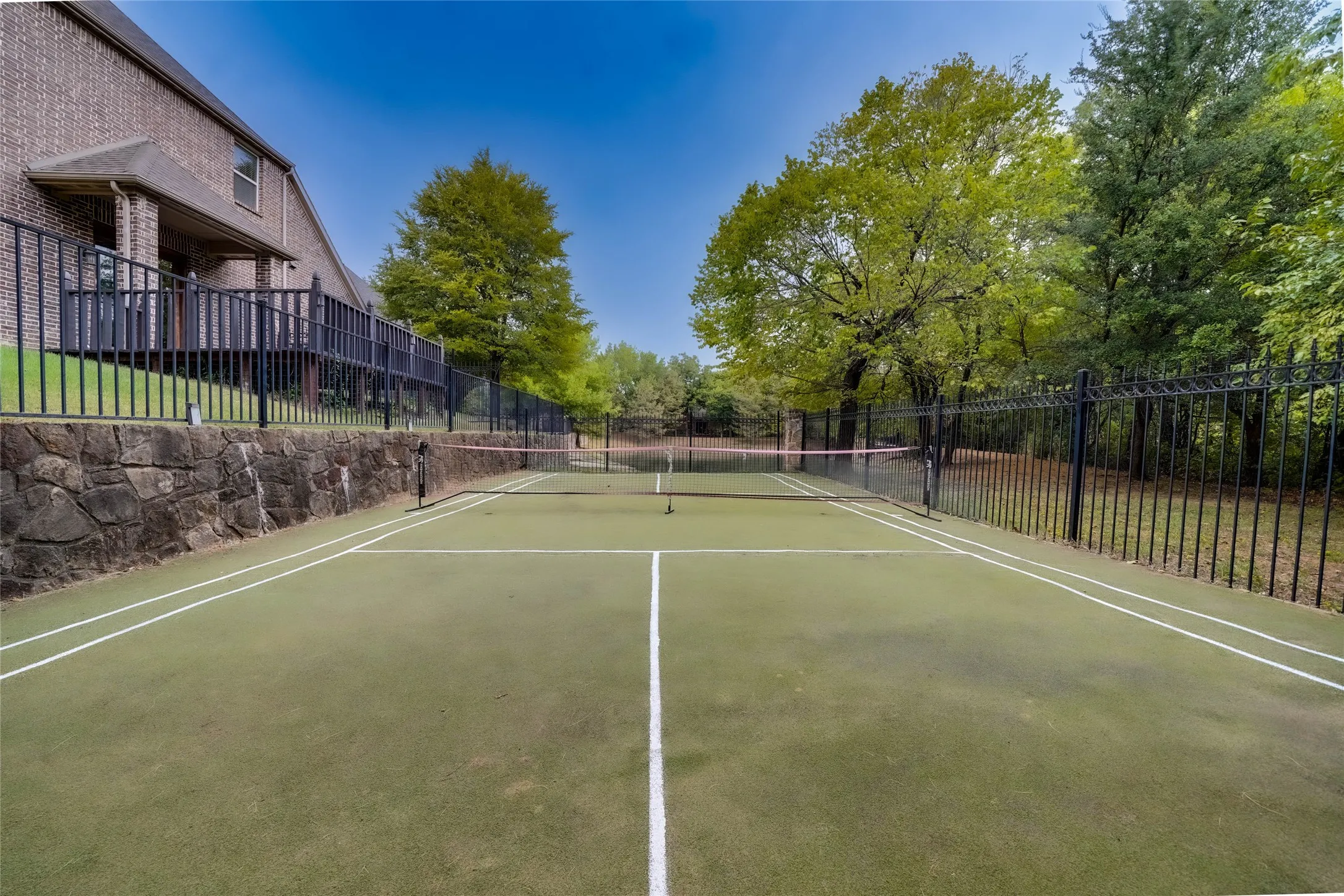 Private tennis court with turf surfacing, full court lines, and a durable net