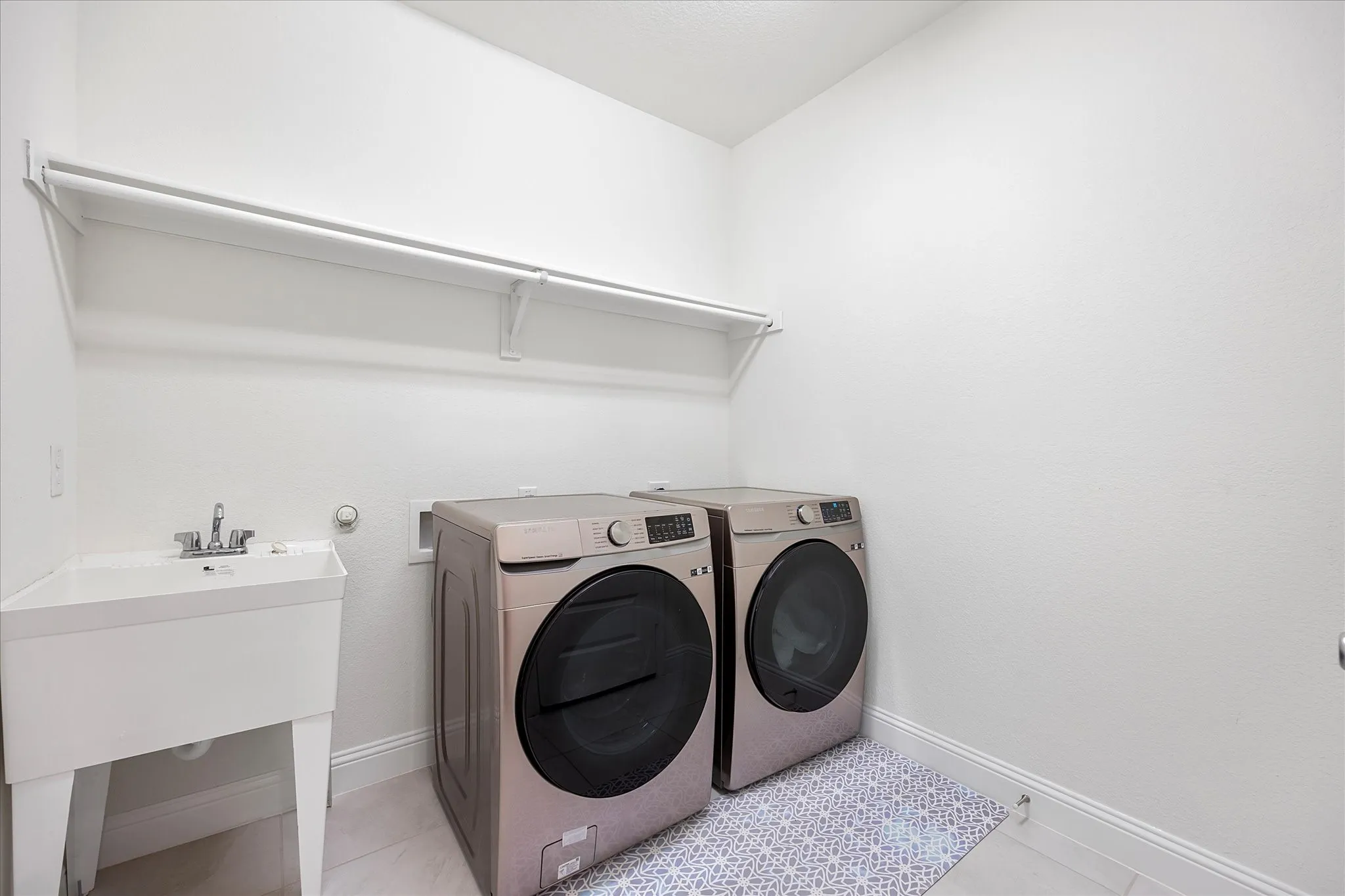 Laundry room includes sink, space for washer & dryer, hanging rod and utility closet