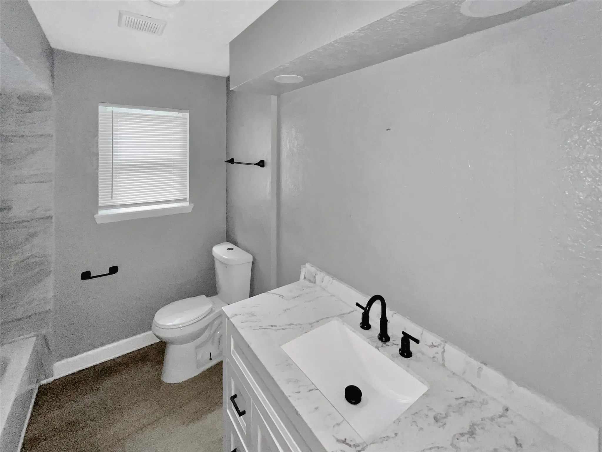 Bathroom featuring a modern vanity with a marble-finish countertop, undermount sink, and matte black faucet