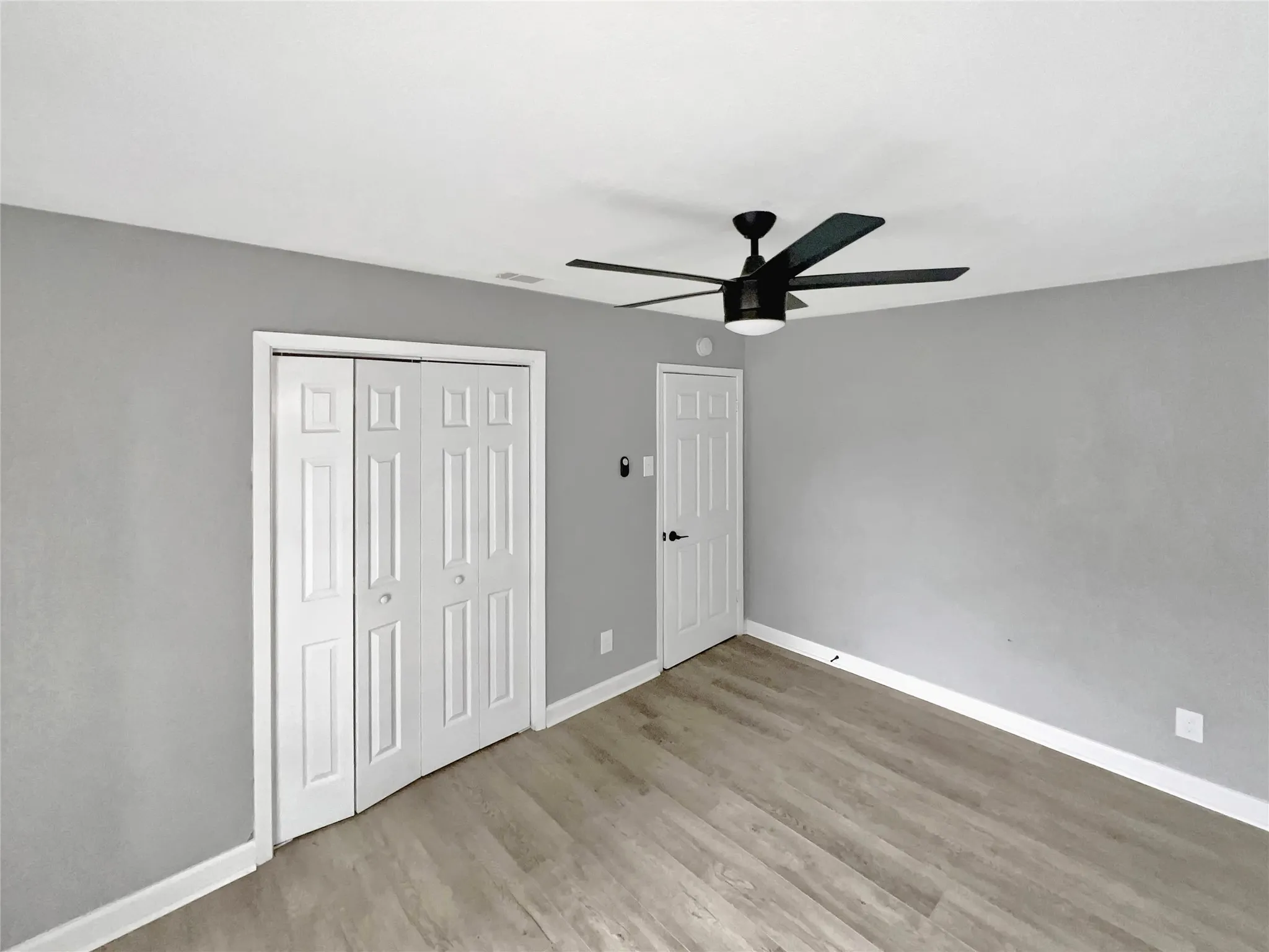 Room featuring light wood-finish flooring, light gray wall paint, and white baseboards