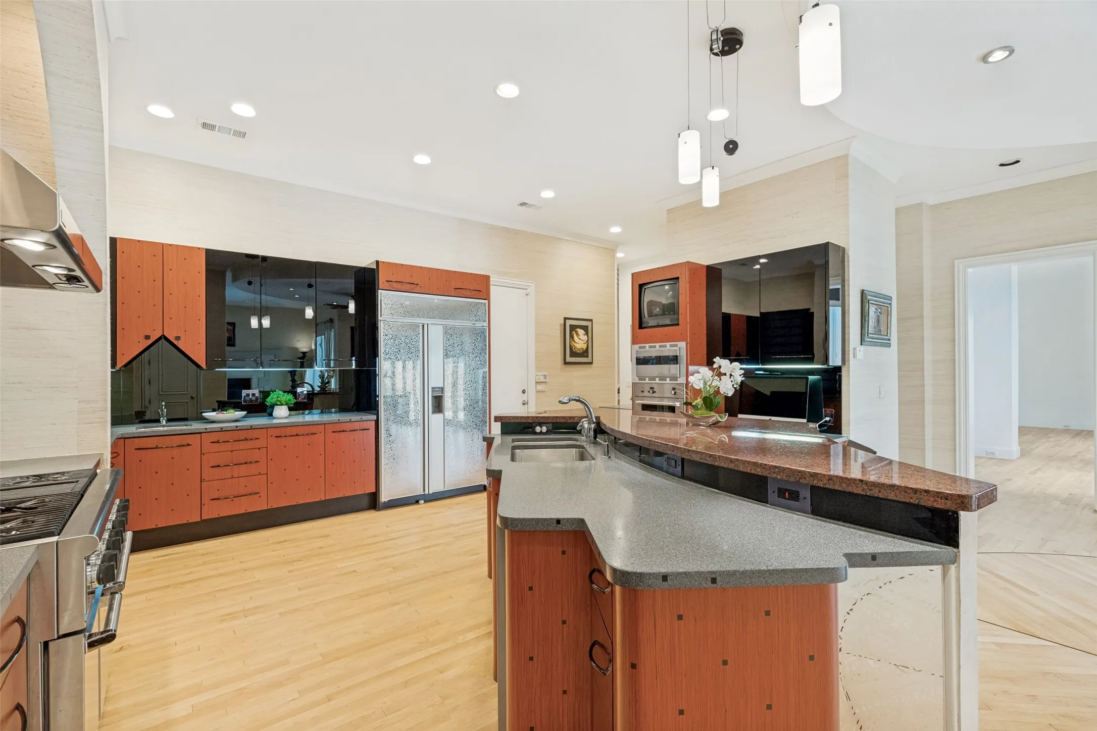 Kitchen featuring wood-finish cabinetry, stainless steel appliances, recessed lighting, and a multi-level island with a built-in sink and countertop seating