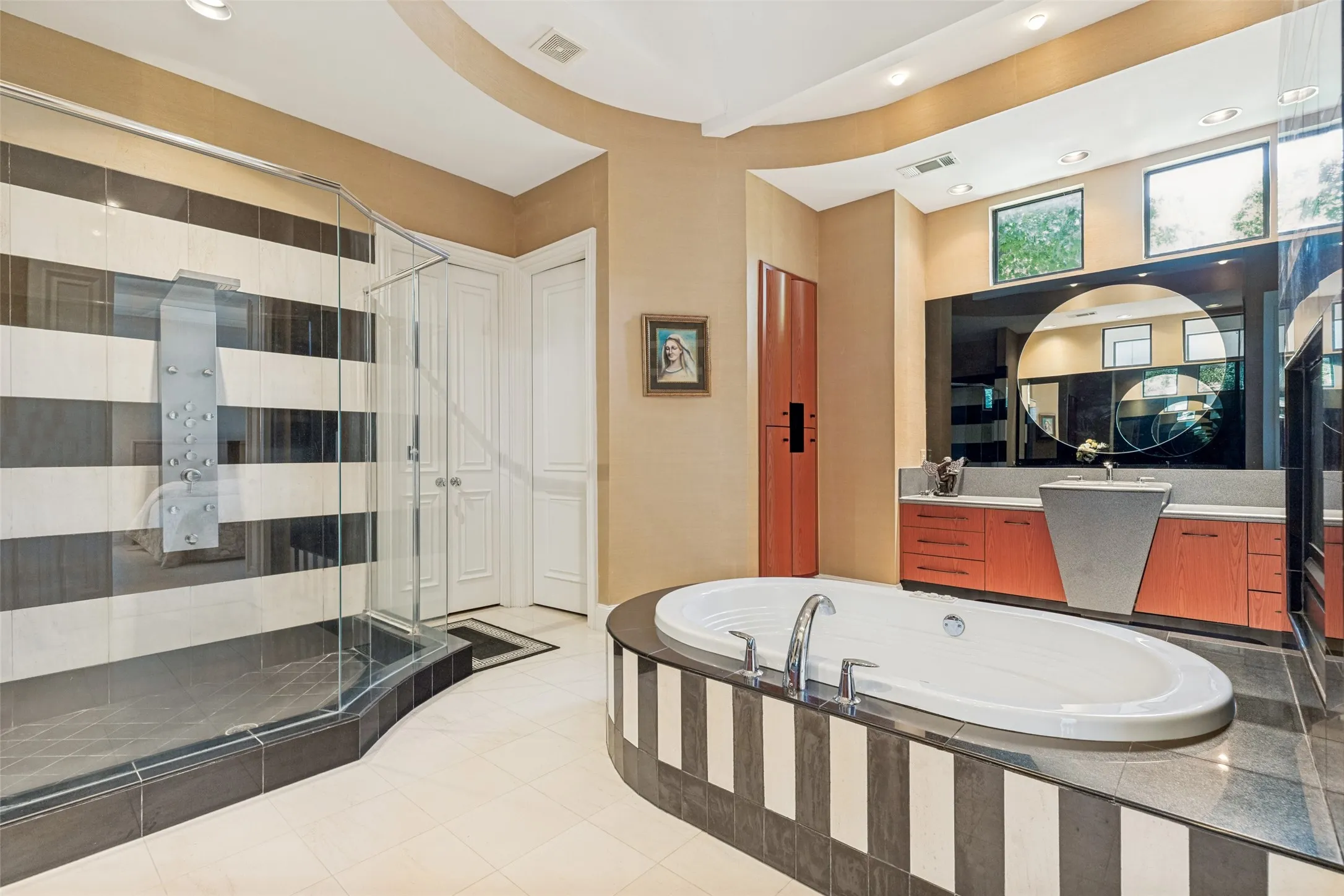 Contemporary bathroom featuring a large soaking tub with integrated deck, a glass-enclosed shower with body jets, a pedestal sink, and a vanity with abundant cabinetry