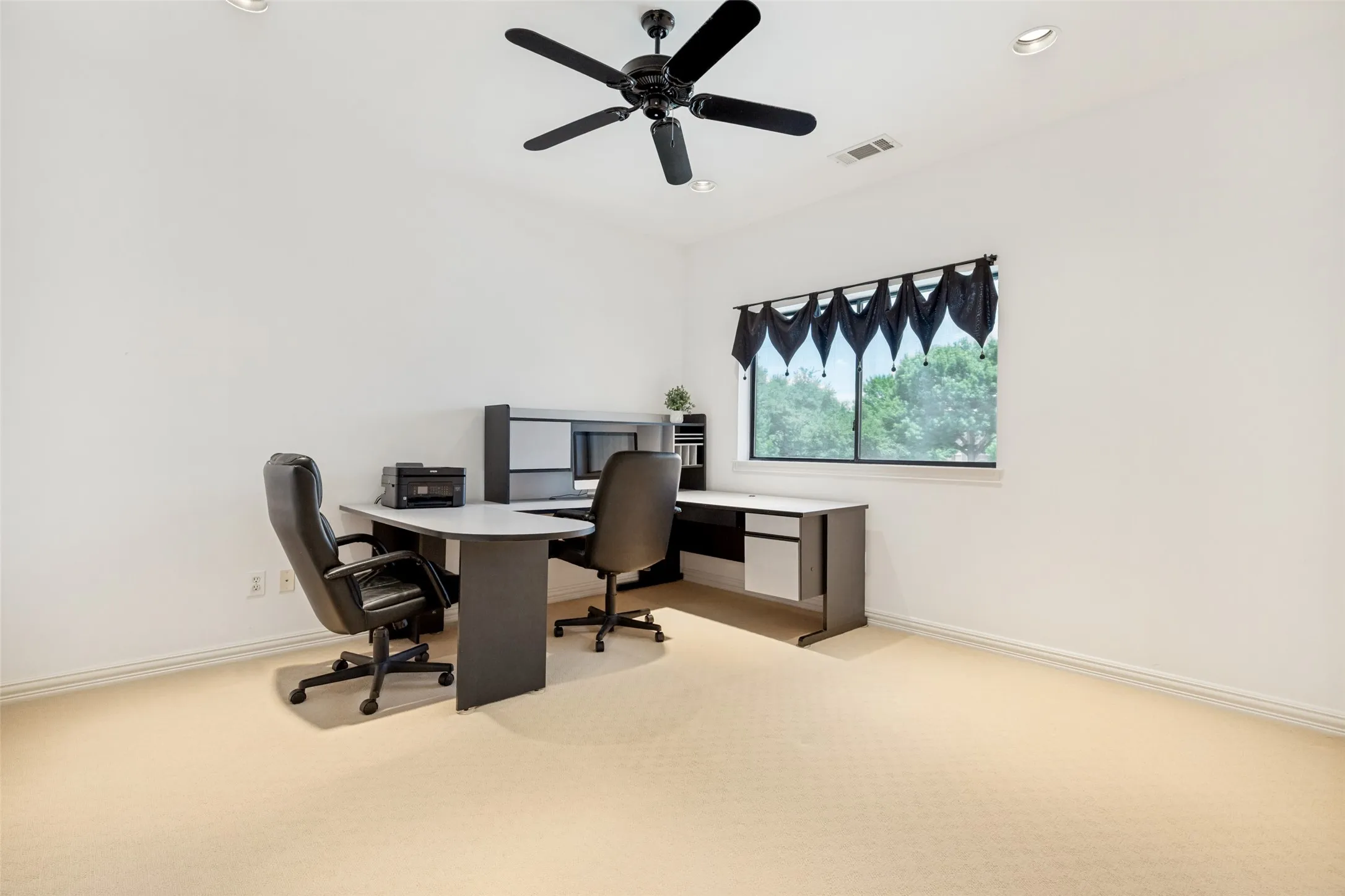 Spacious room featuring neutral carpeting, a black ceiling fan with integrated lighting, and recessed ceiling lights
