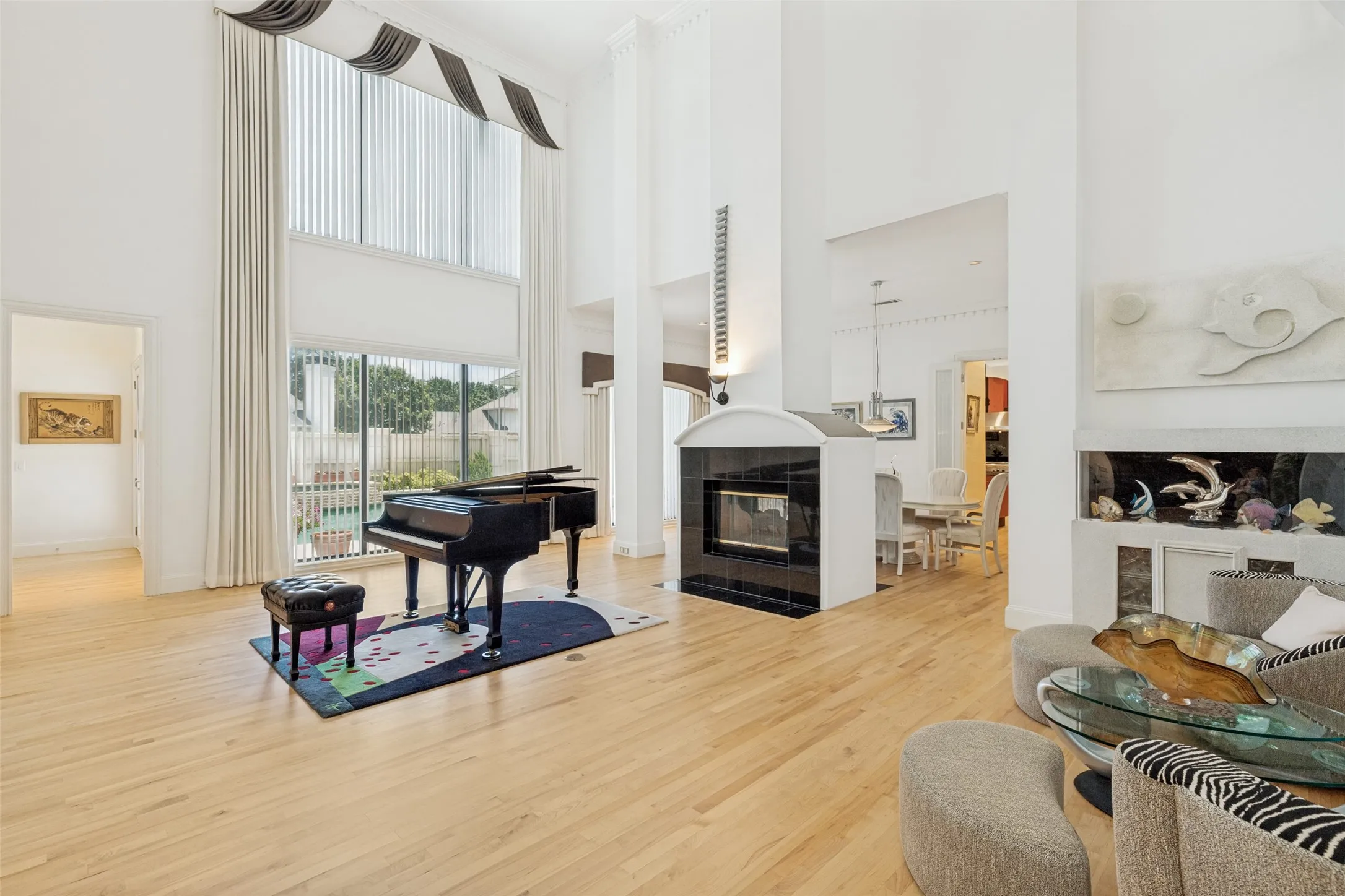 Two-story living area featuring light wood-finish flooring and a black tiled fireplace