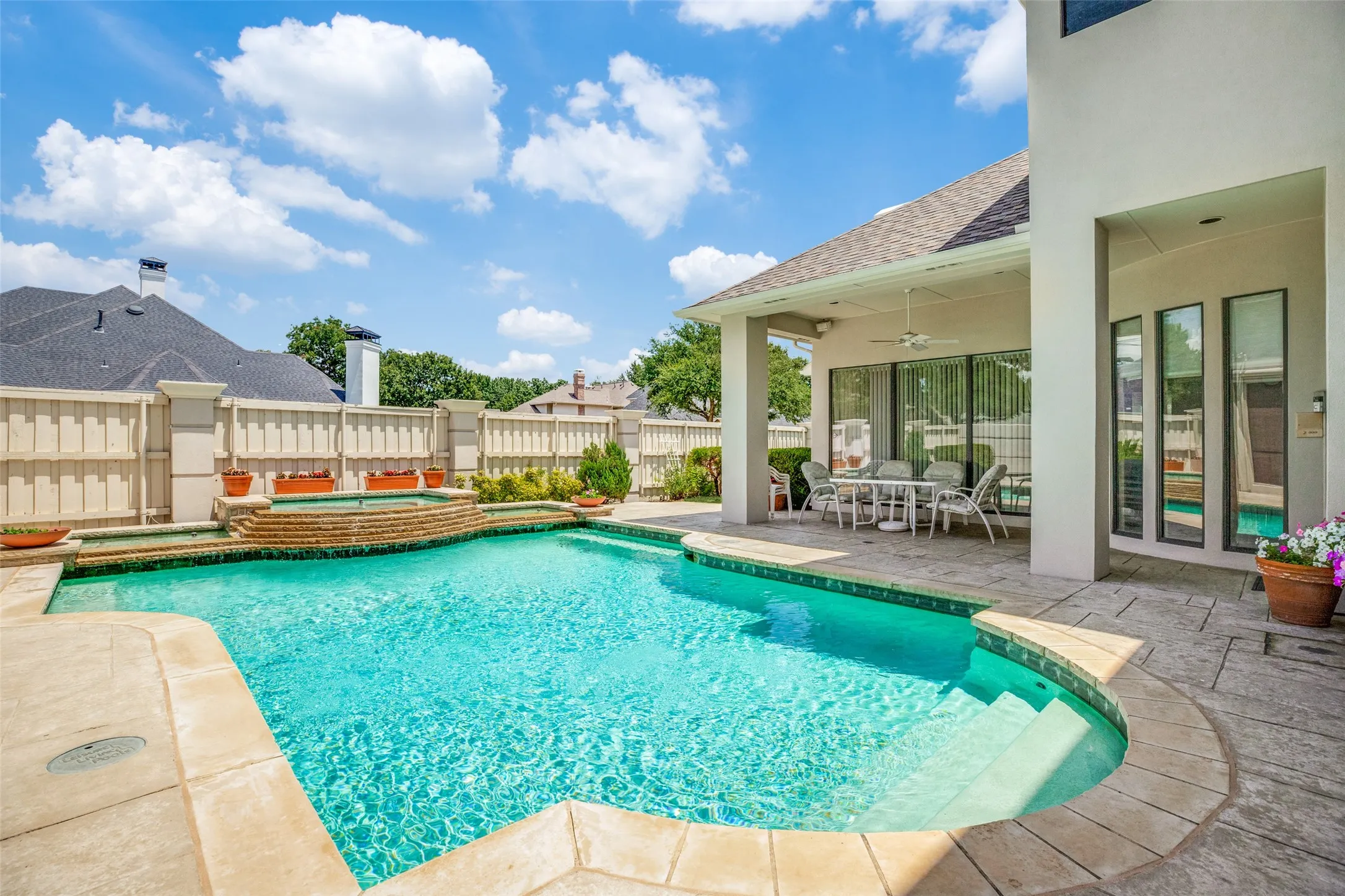 Expansive outdoor living area featuring a swimming pool with integrated spa and stone coping