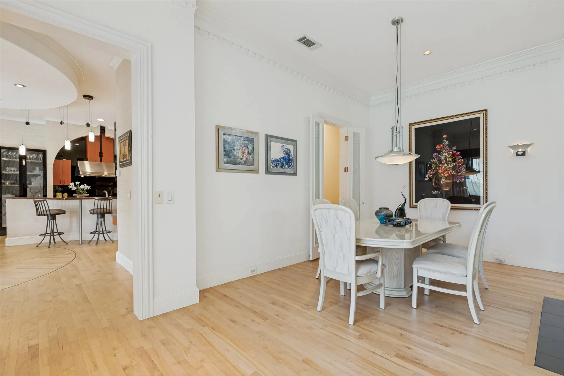 Dining area featuring hardwood flooring, decorative crown molding, and a pendant light fixture
