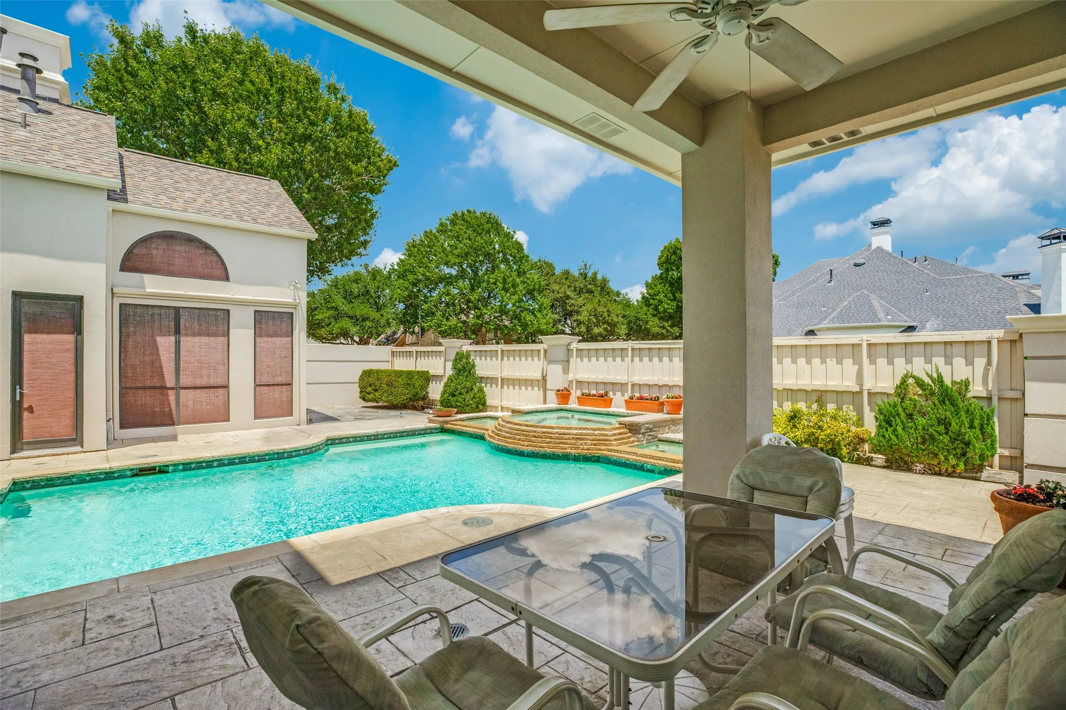Covered patio with stamped concrete flooring, ceiling fan, and direct access to the swimming pool and elevated spa