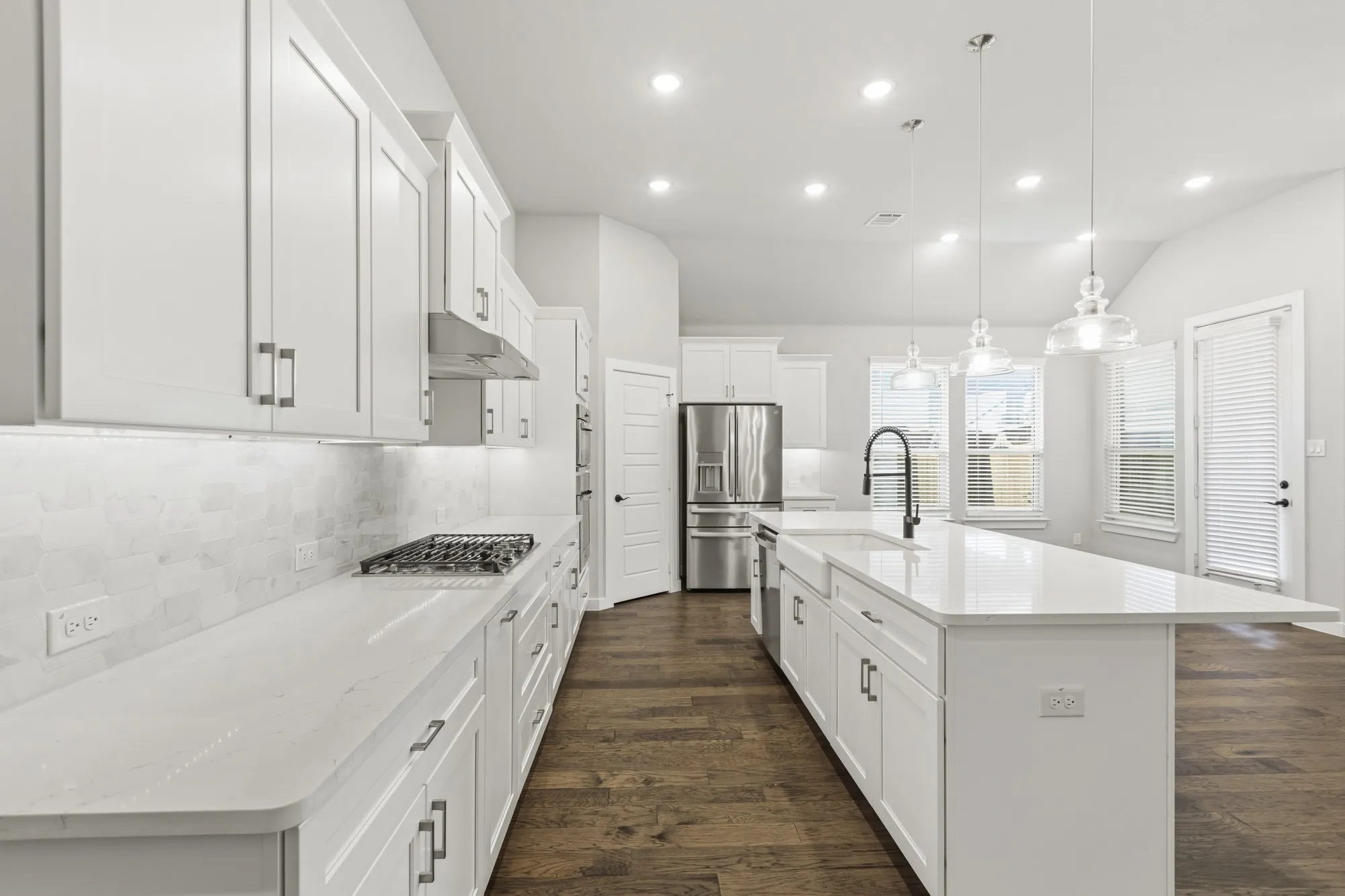 Modern kitchen featuring white cabinetry, light-toned countertops, a gas cooktop, and wood-finish flooring