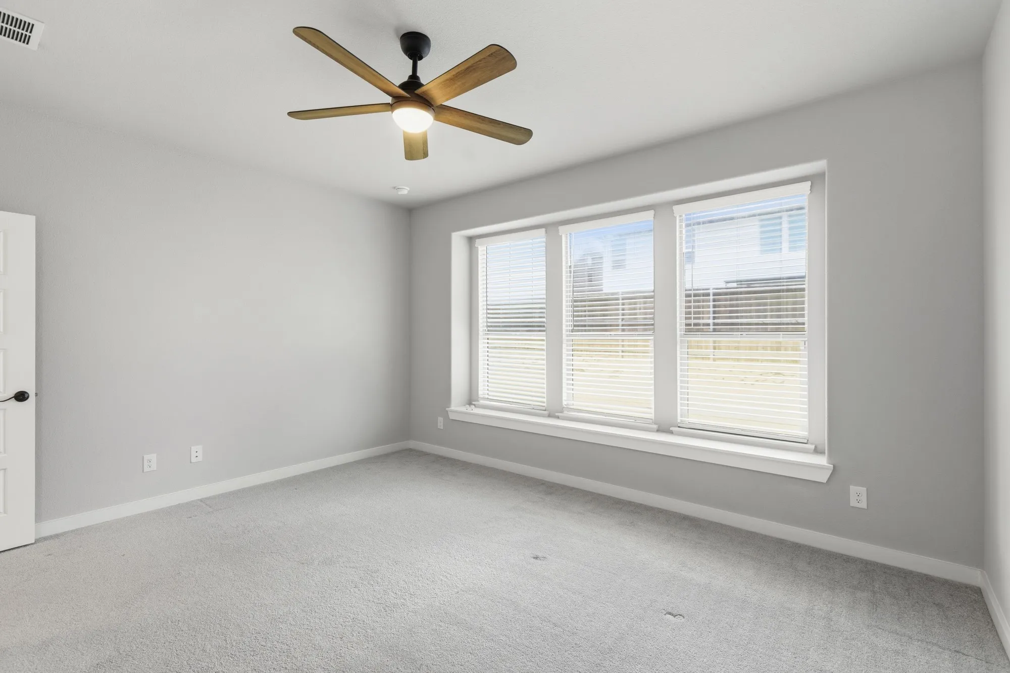 Room featuring light gray walls, gray carpeting, and a multi-pane window with white blinds