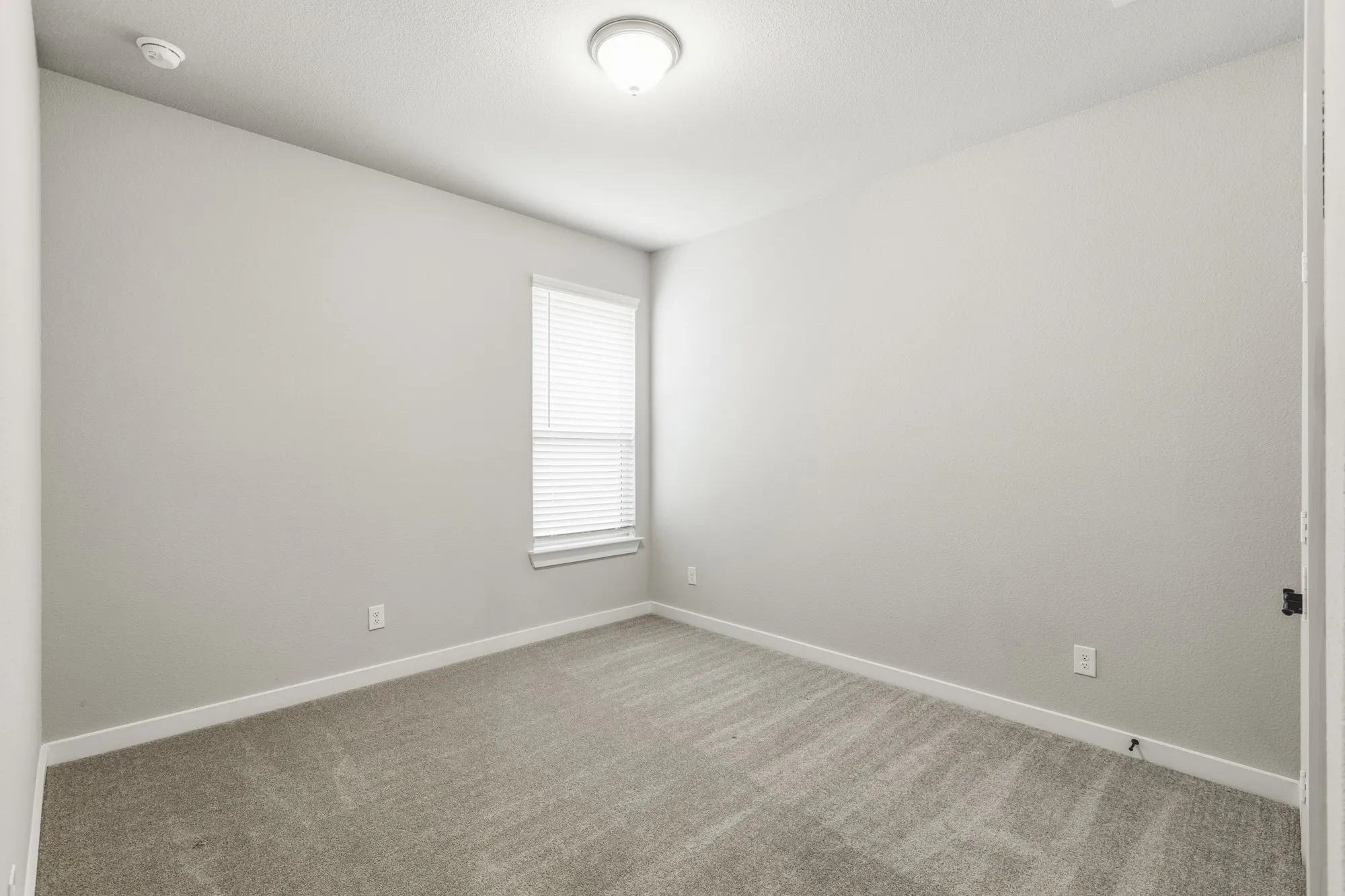 Neutral-toned interior room featuring light gray walls, white trim, and gray patterned carpet