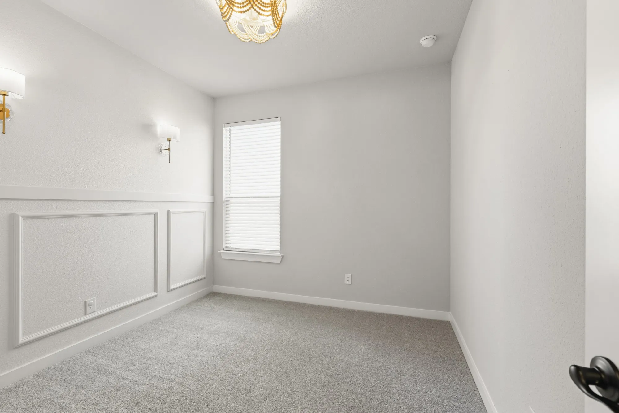Room featuring wainscoting detail, neutral carpeting, and a window with blinds