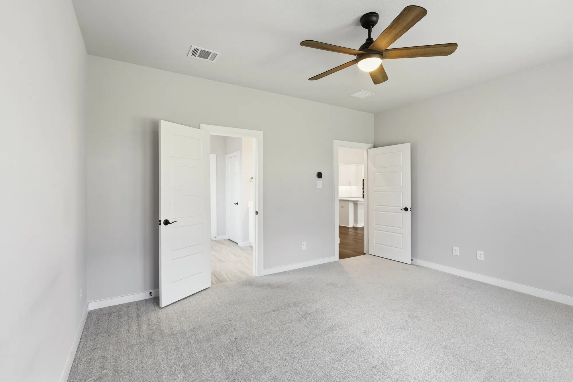 Spacious room featuring light gray carpeting and two paneled interior doors with matte black hardware