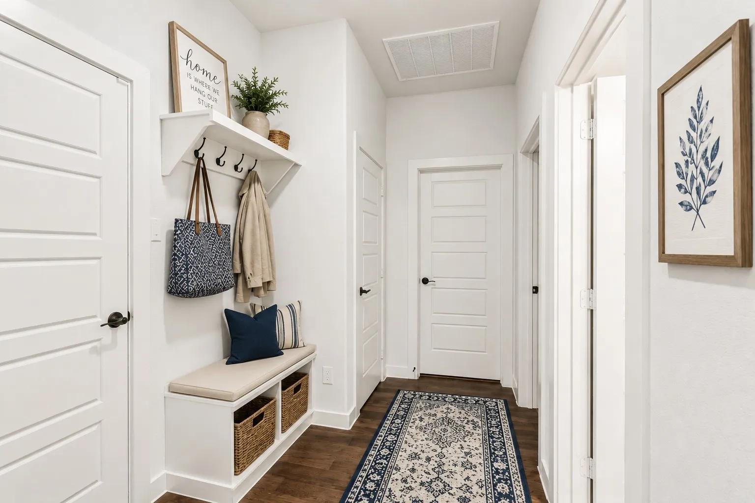 Entryway featuring a built-in bench with integrated shelving, matte black hardware, wood-finish flooring, and crisp white trim