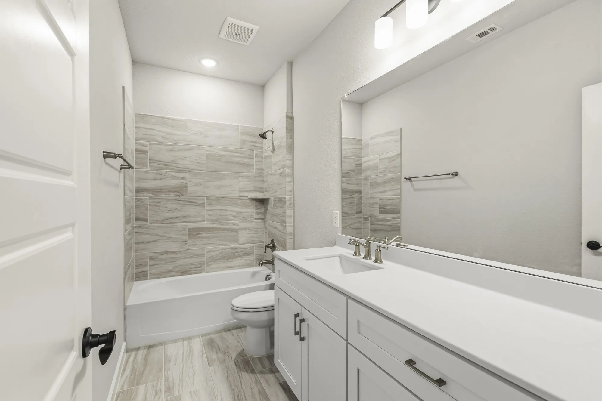 Bathroom featuring a vanity with integrated sink, white cabinetry, and a full-width mirror