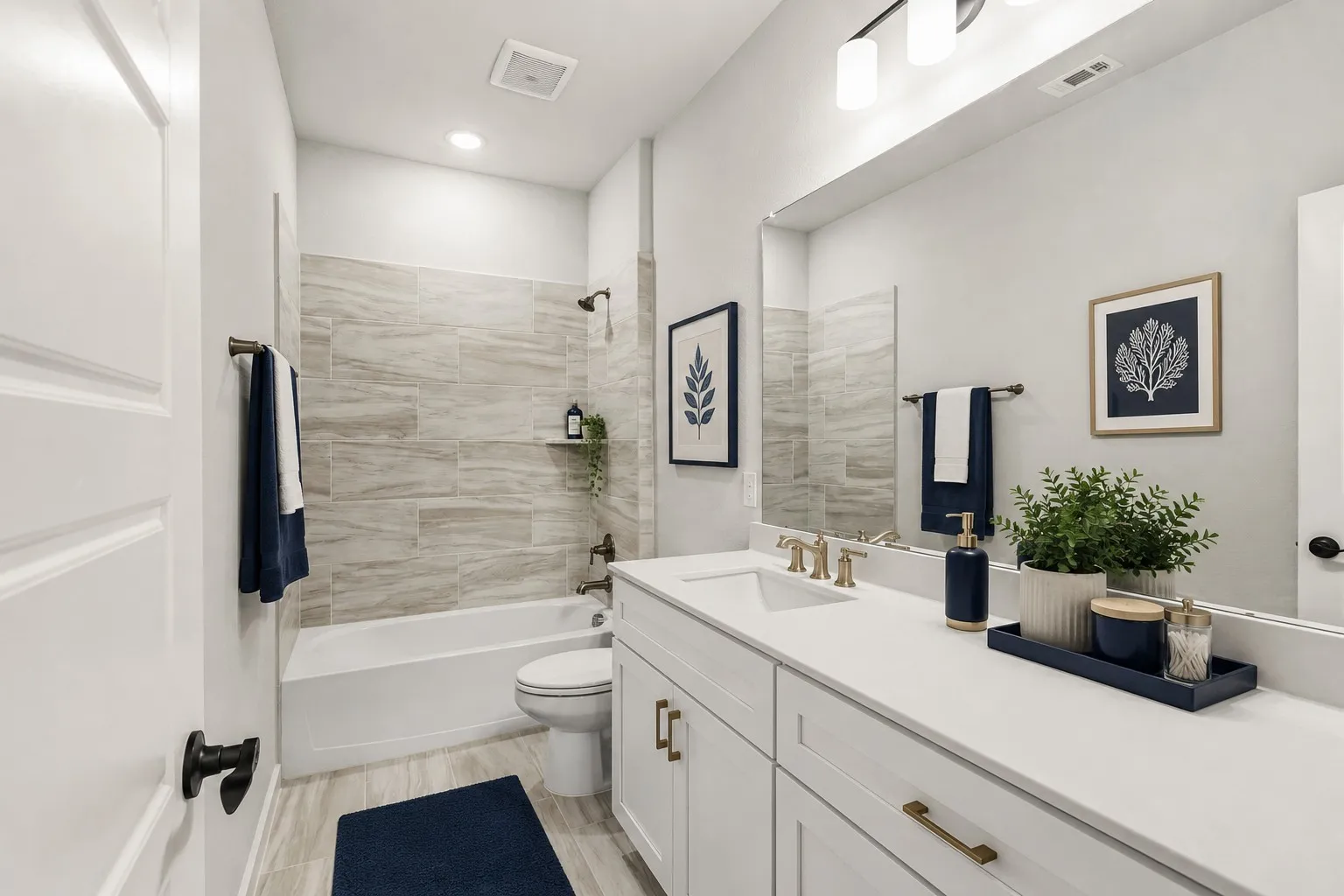 Contemporary bathroom featuring a white vanity with gold-finish hardware, a large wall-mounted mirror, and a tub-shower combination with tiled surround