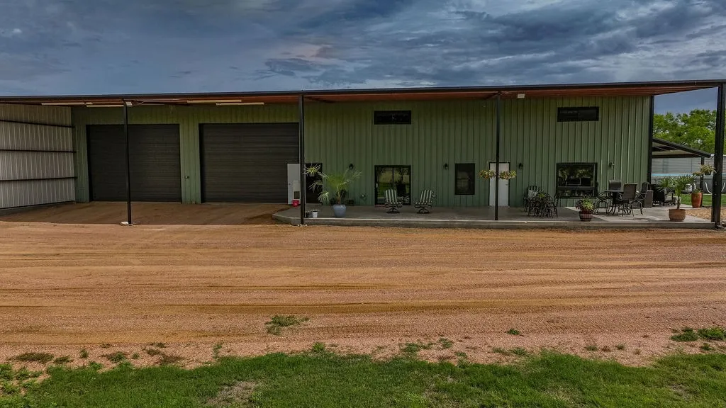 ront of the 9,000 sq ft barndominium. There are two oversized roll up doors, a covered concrete porch and plenty of parking for guests, trucks and trailers.