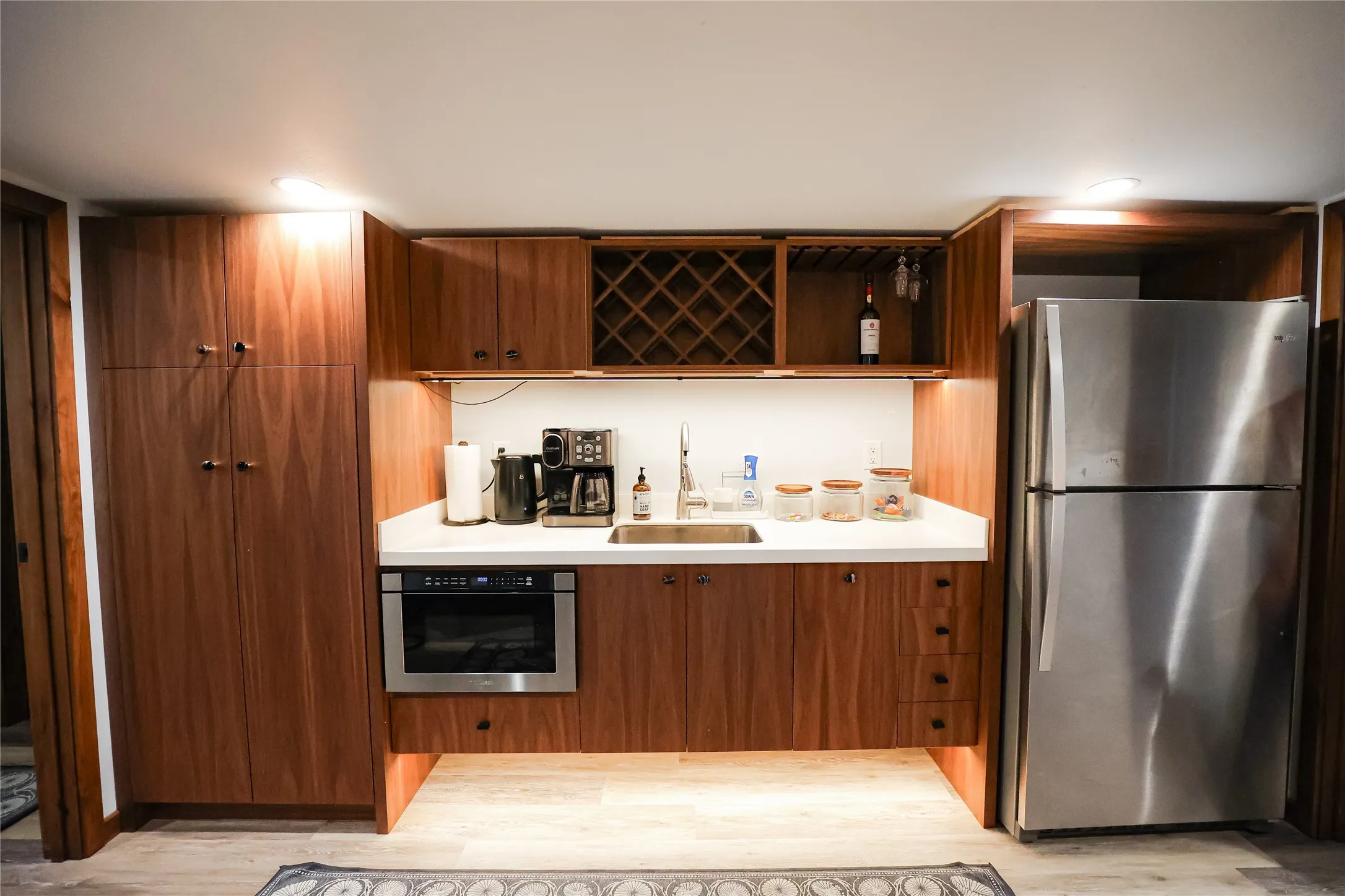 Coffee and cocktail bar with walnut cabinetry, a wine rack, a full size refrigerator and a drawer microwave. It serves the private keyed guest rooms upstairs.