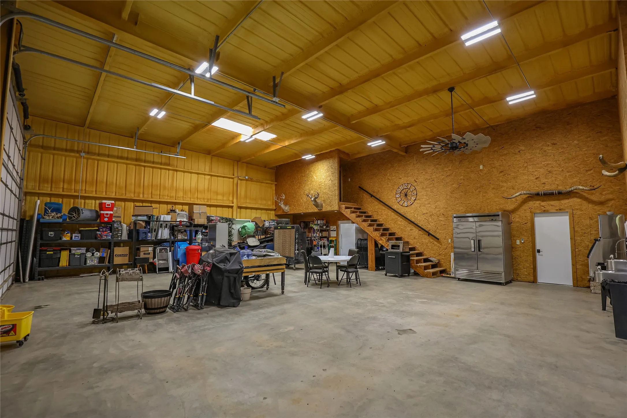 Shop interior with stairs to a loft, sealed concrete floor and room for equipment, a game room or a hunting camp gathering space.