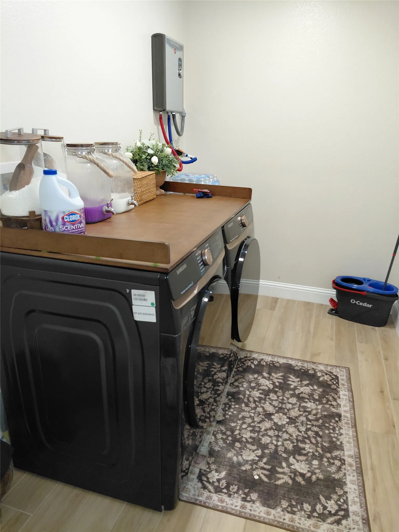 Utility area featuring a wall-mounted tankless water heater, wood-finish countertop, and light wood-look flooring