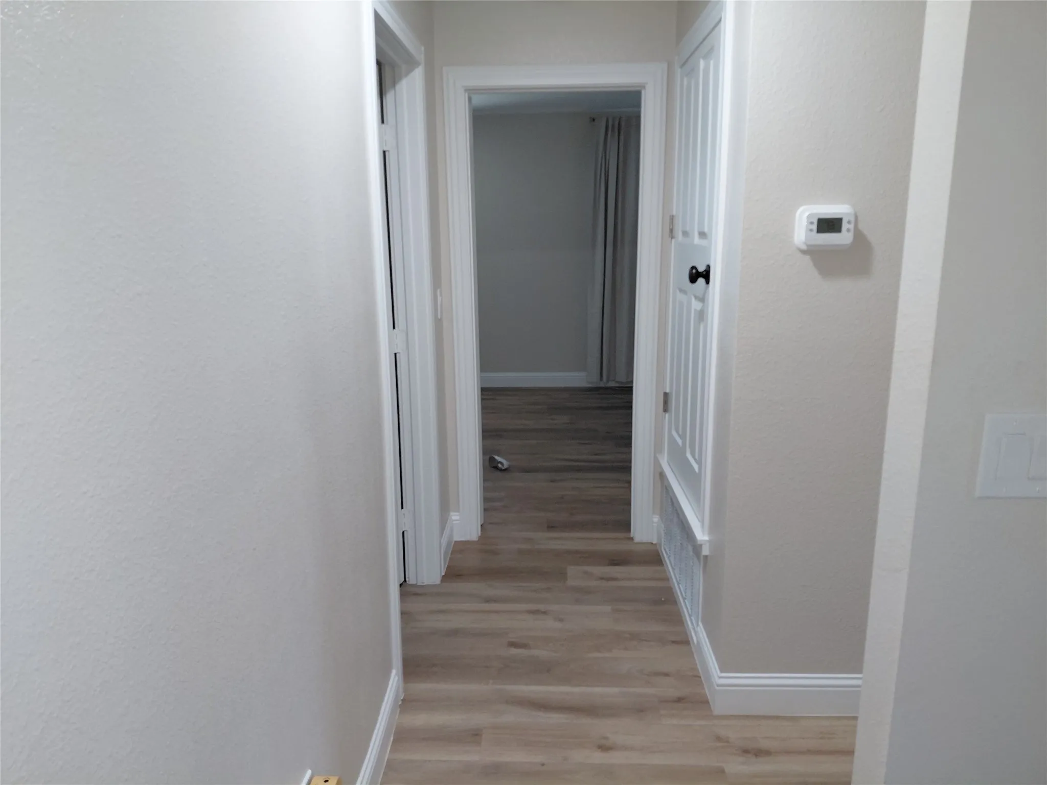 Hallway featuring wood-finish flooring, white baseboards, and neutral wall tones