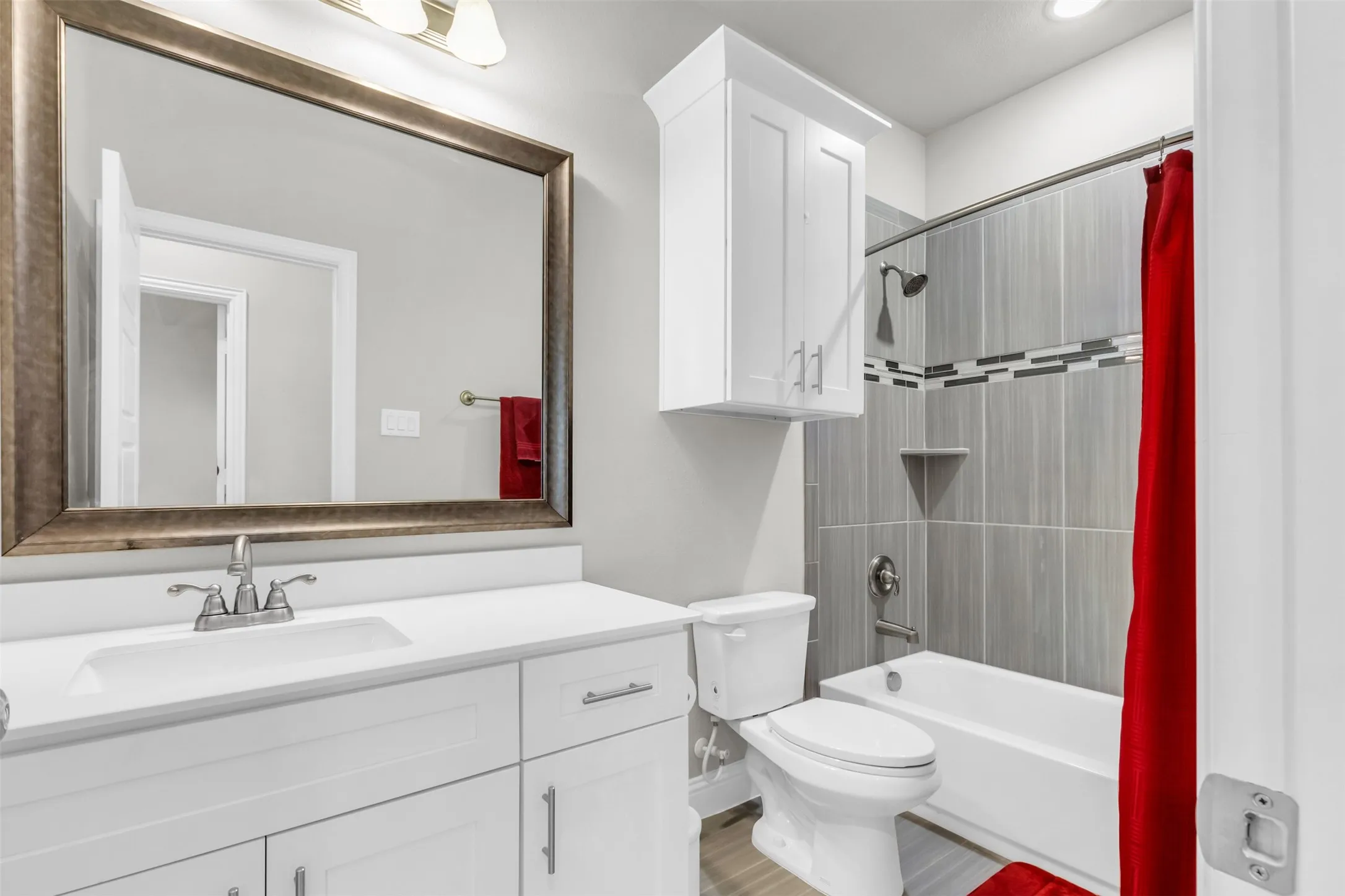 Bathroom featuring a single vanity with an undermount sink, a large framed mirror, and white cabinetry