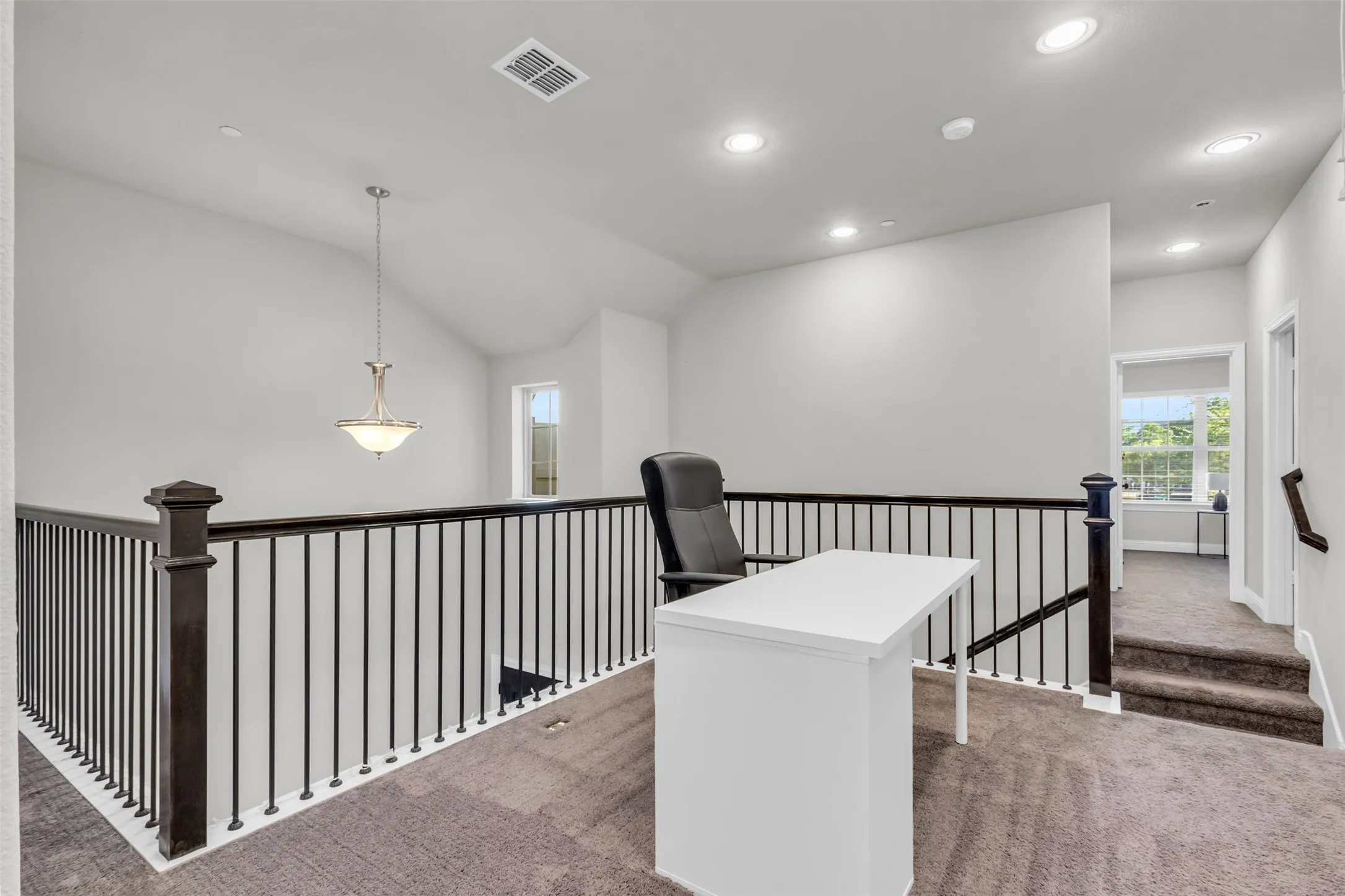 Open loft area featuring a wrought iron and wood railing, recessed lighting, vaulted ceiling, and carpeted flooring